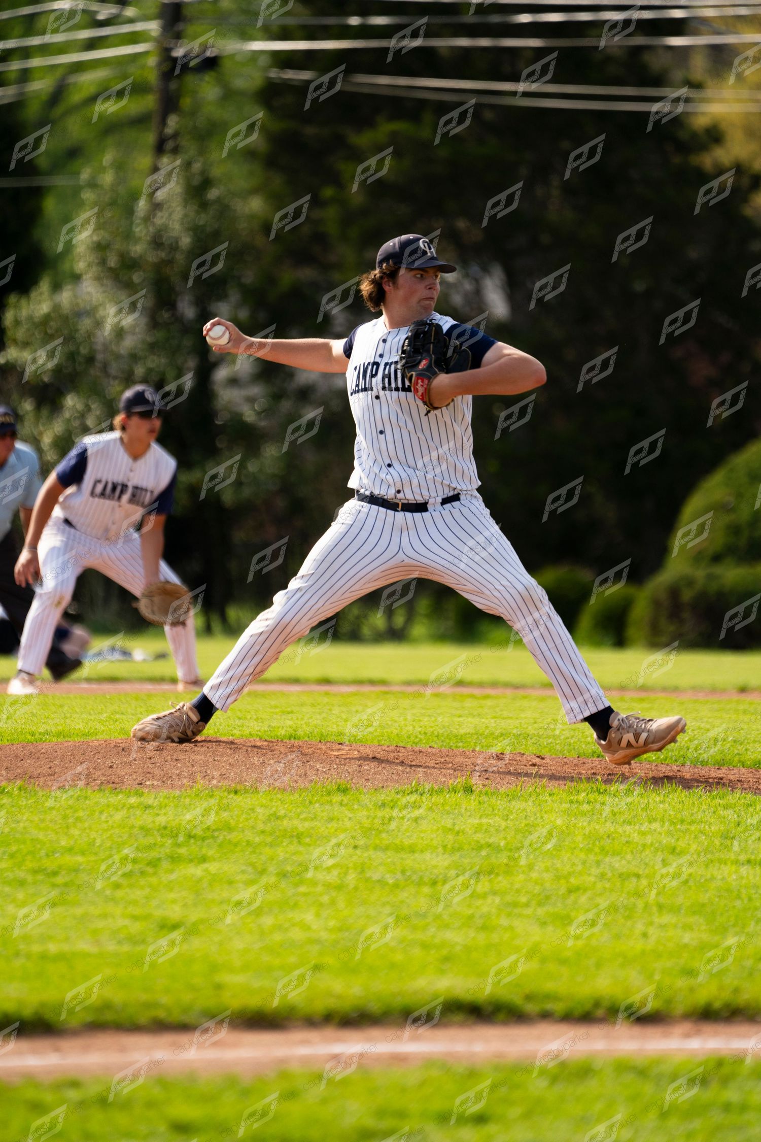 Camp Hill pitcher releases a pitch from the mound with a fielder visible in background.