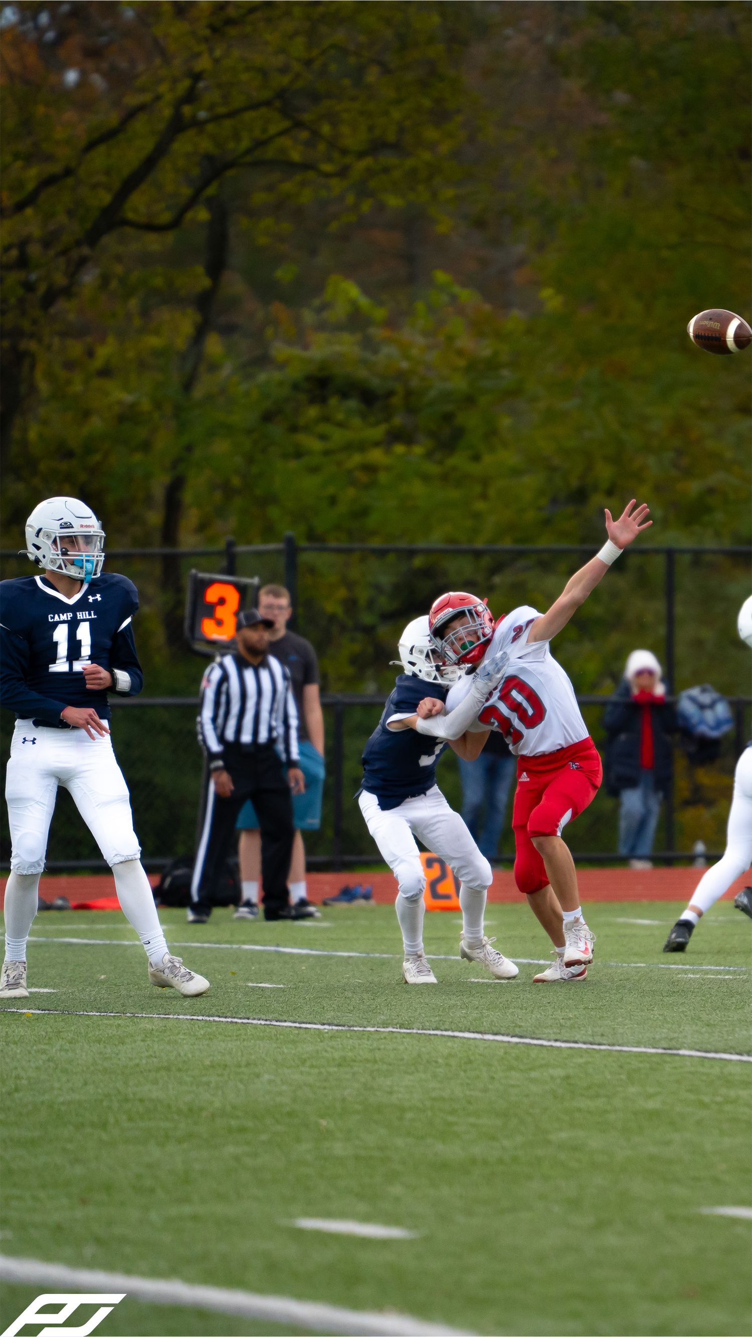 Youth quarterback number 11 in navy releases a pass while red-uniformed defender attempts to block the throw.