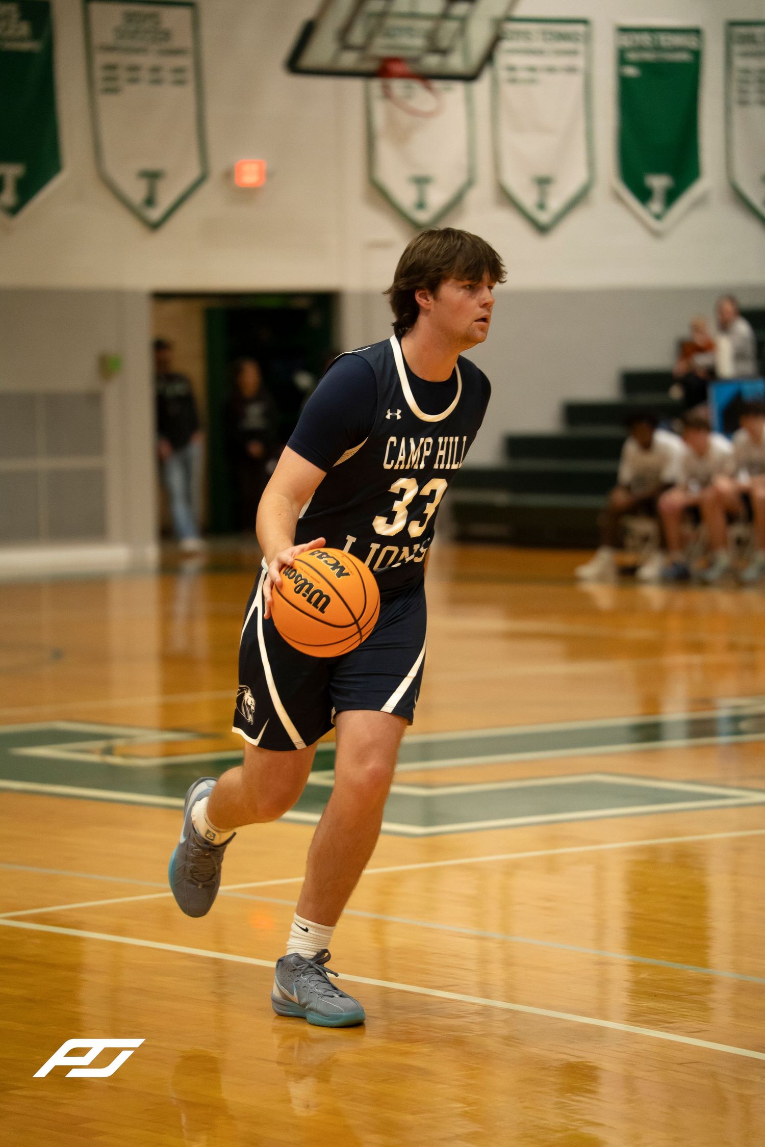 Camp Hill Lions number 33 dribbles the basketball during a high school varsity game.