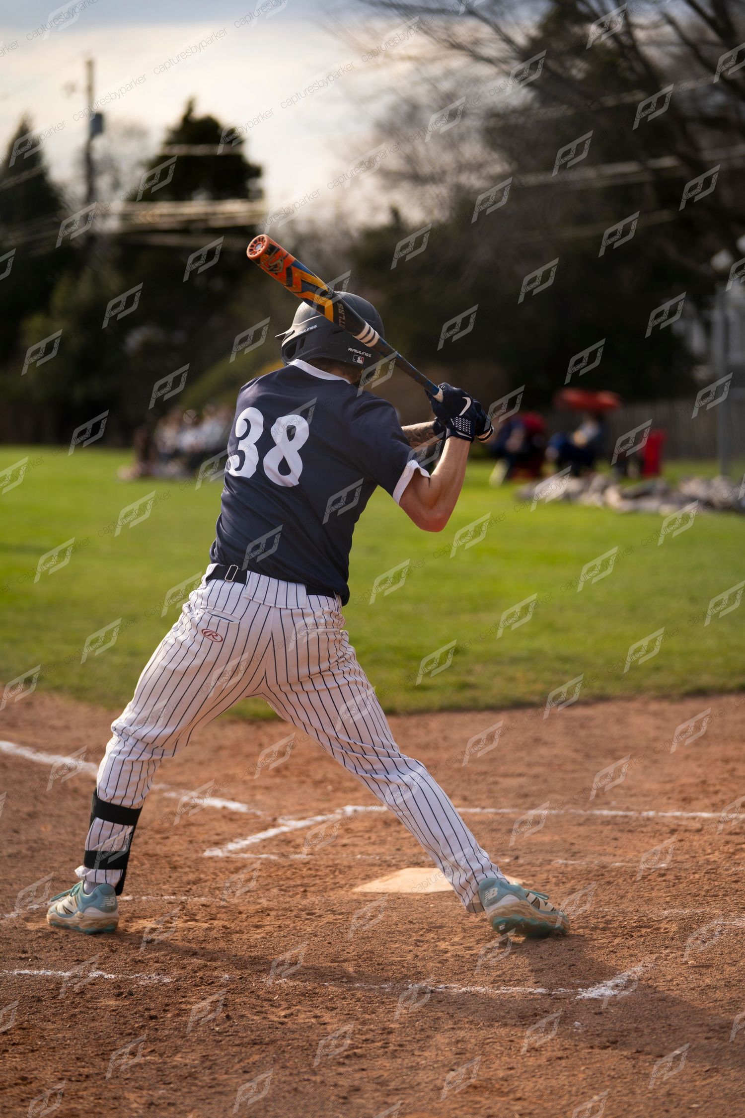 Baseball batter #38 swings at a pitch during an outdoor game at golden hour.