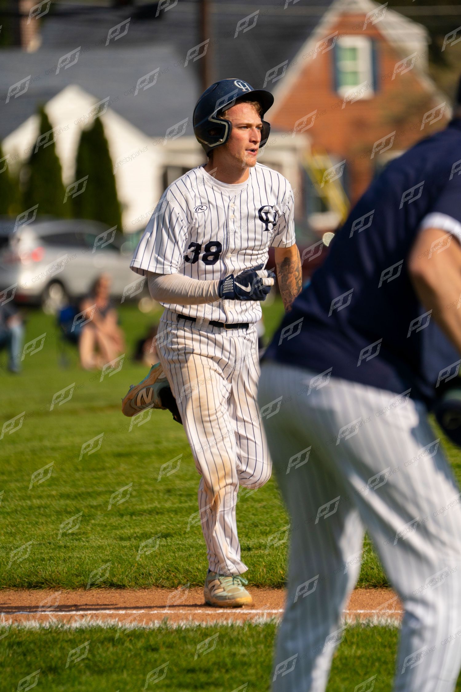 Baseball player #38 in white pinstripe uniform runs the bases during a sunny outdoor game.