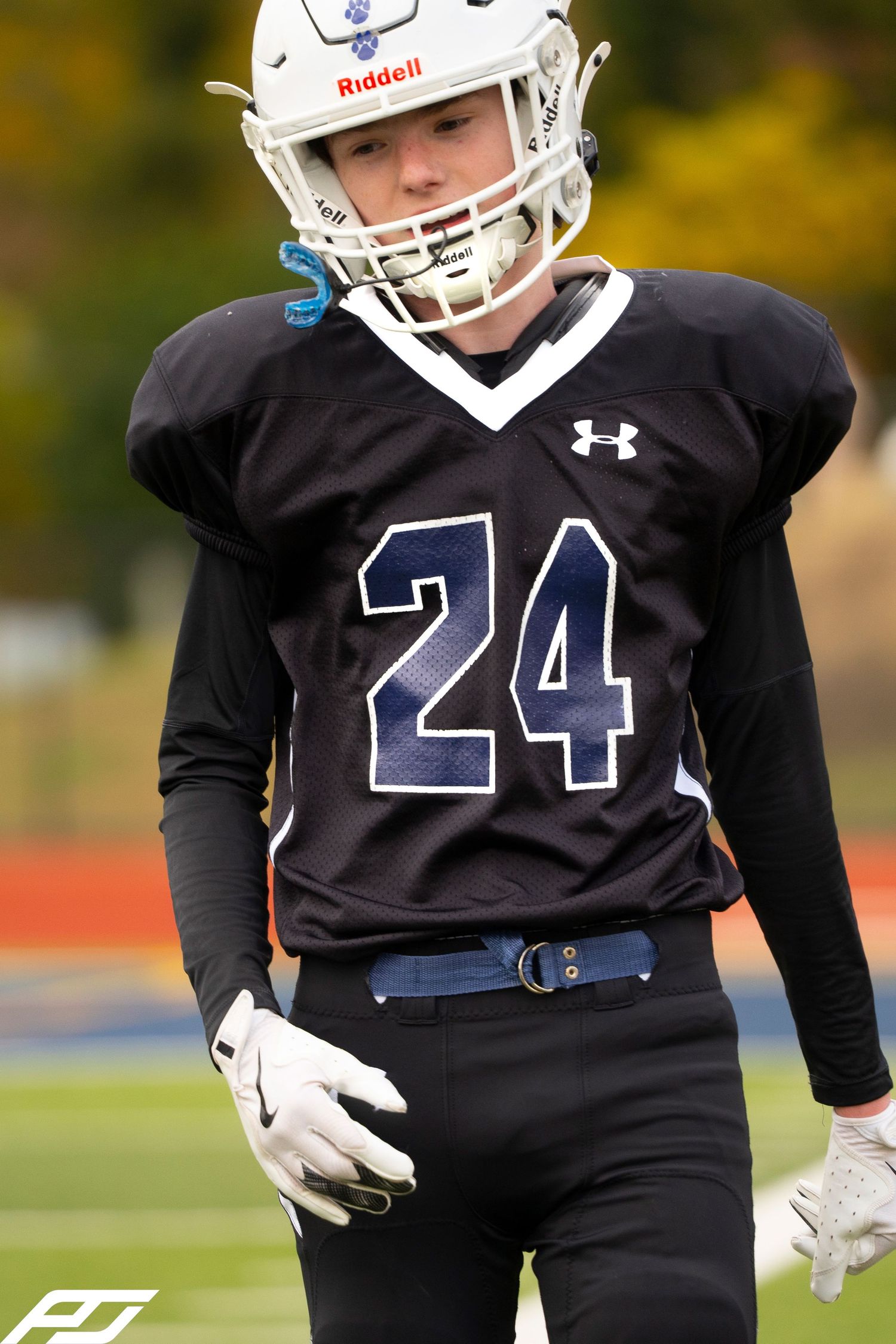 Close-up of youth football player number 24 wearing a Riddell helmet and Under Armour black jersey with white gloves.