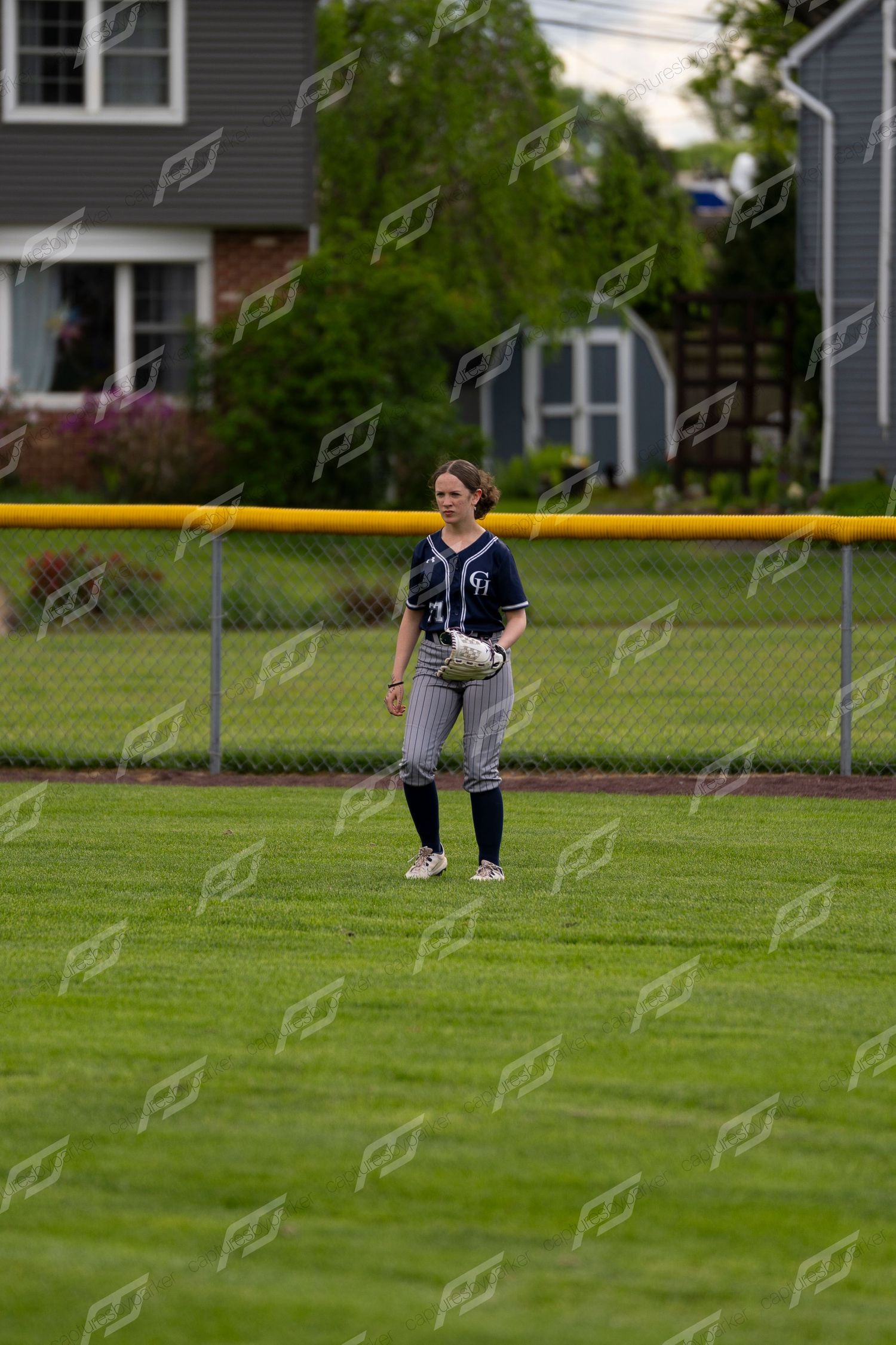 Female softball outfielder standing in the grass field during a youth softball game.