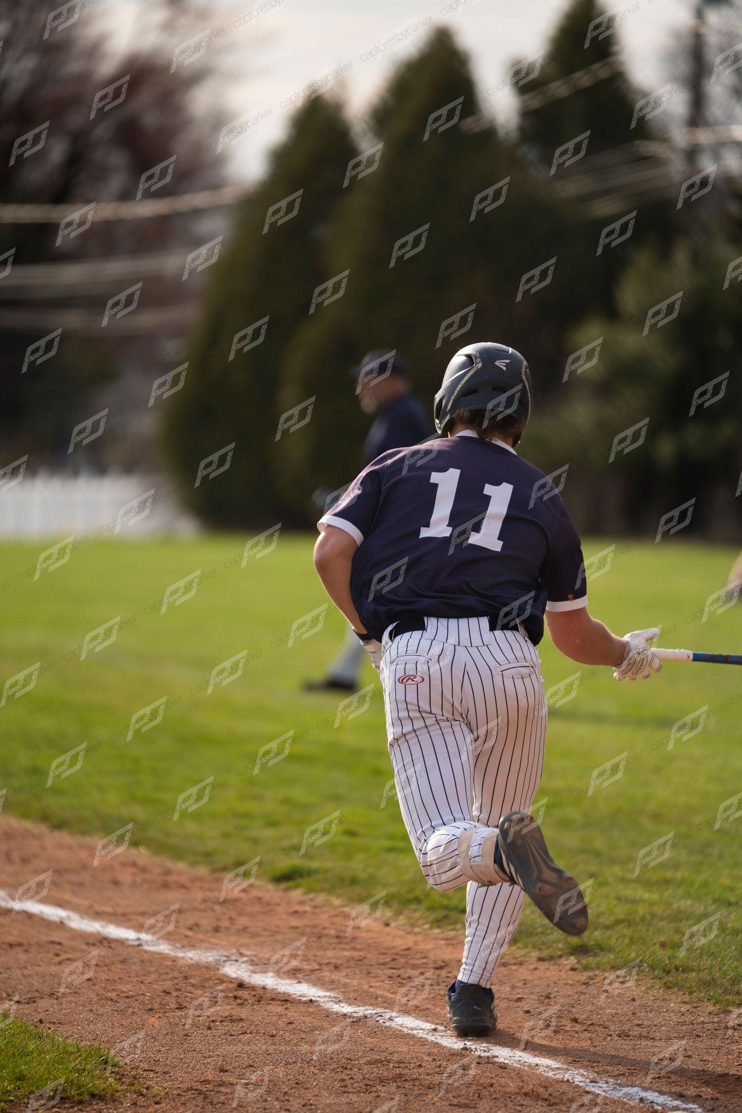 Baseball player #11 in navy pinstripe uniform running the baseline holding a bat.