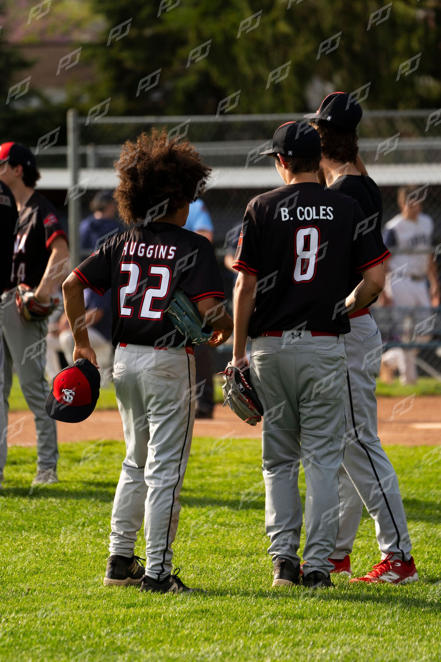 Two youth baseball players in black uniforms, #22 Huggins and #8 B. Coles, stand together on the field.