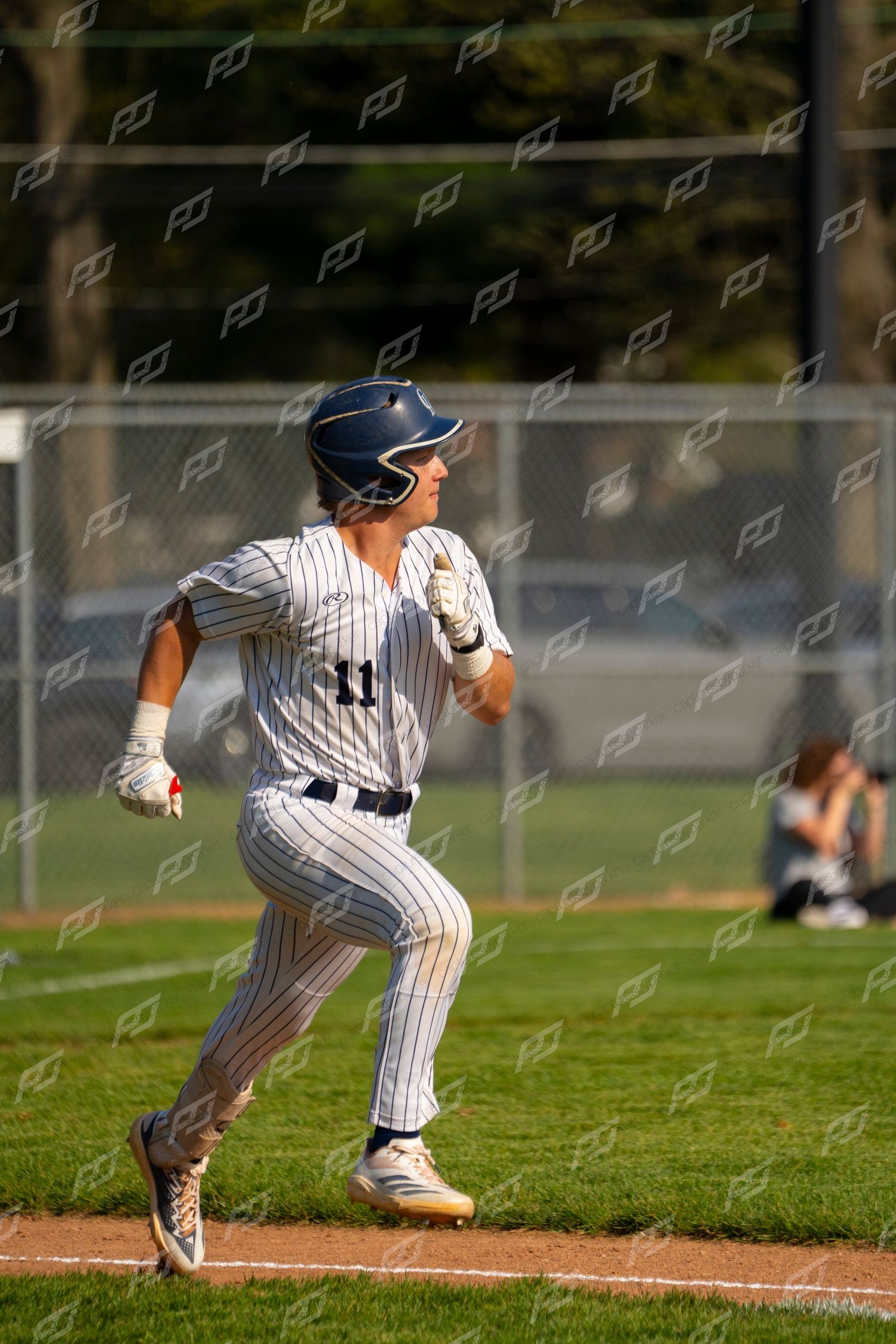 Baseball player #11 in pinstripe uniform sprints from home plate after making contact.