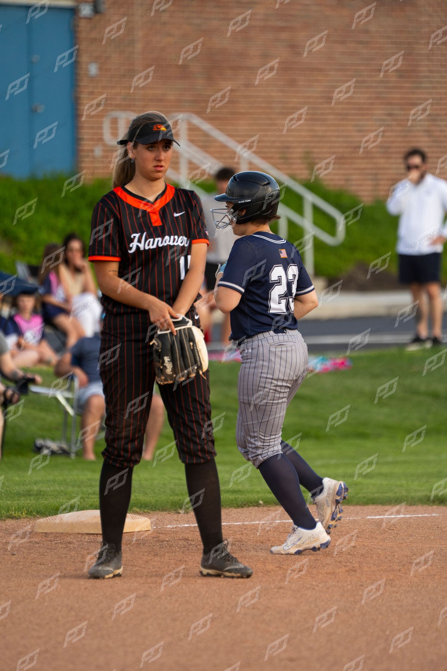 Hanover softball fielder stands at first base as opposing player number 27 runs past.