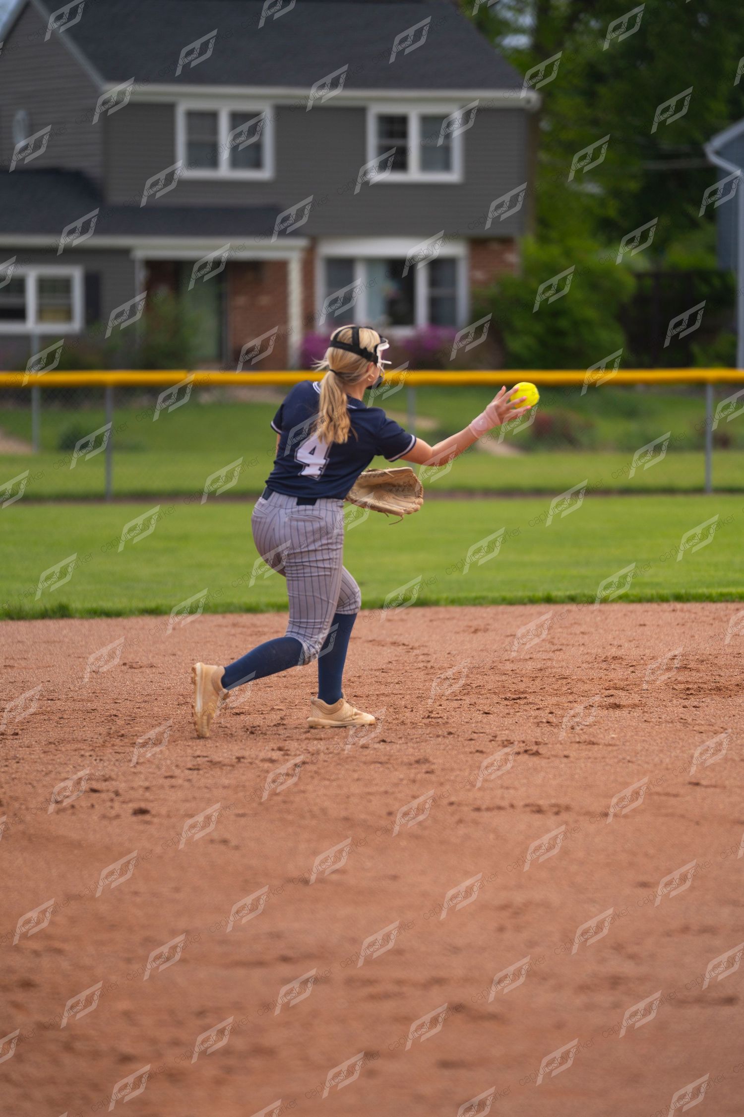Softball player number 4 in navy uniform prepares to throw the yellow ball.
