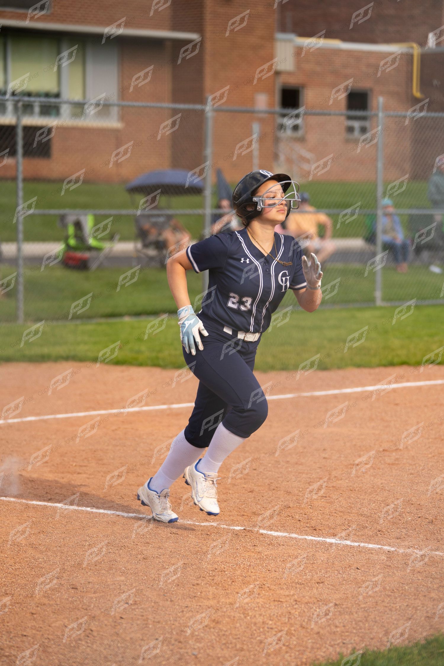 Softball player number 23 in navy CH uniform runs the bases during an evening game.