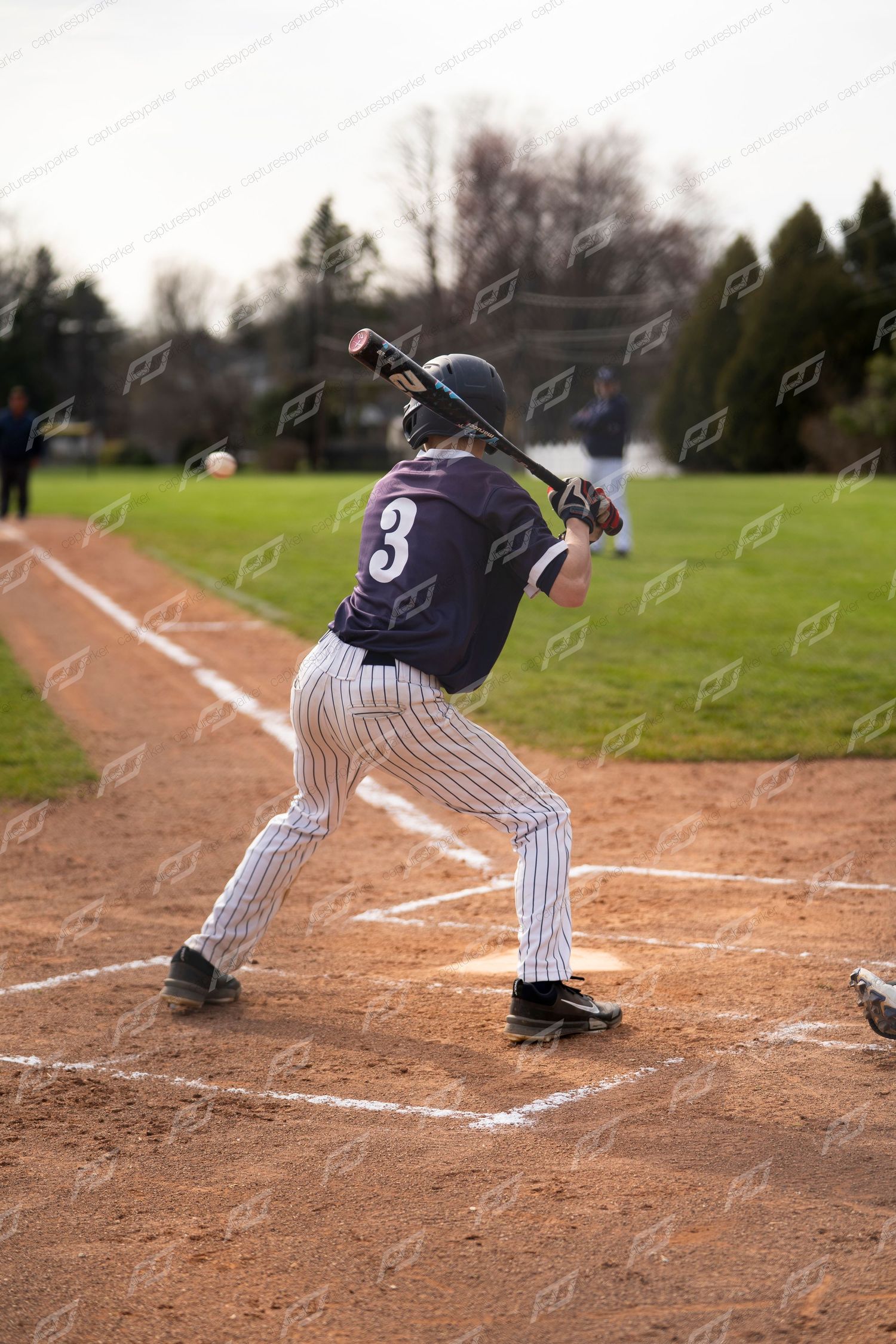 Youth baseball batter #3 in pinstripe pants makes contact at home plate during a game.