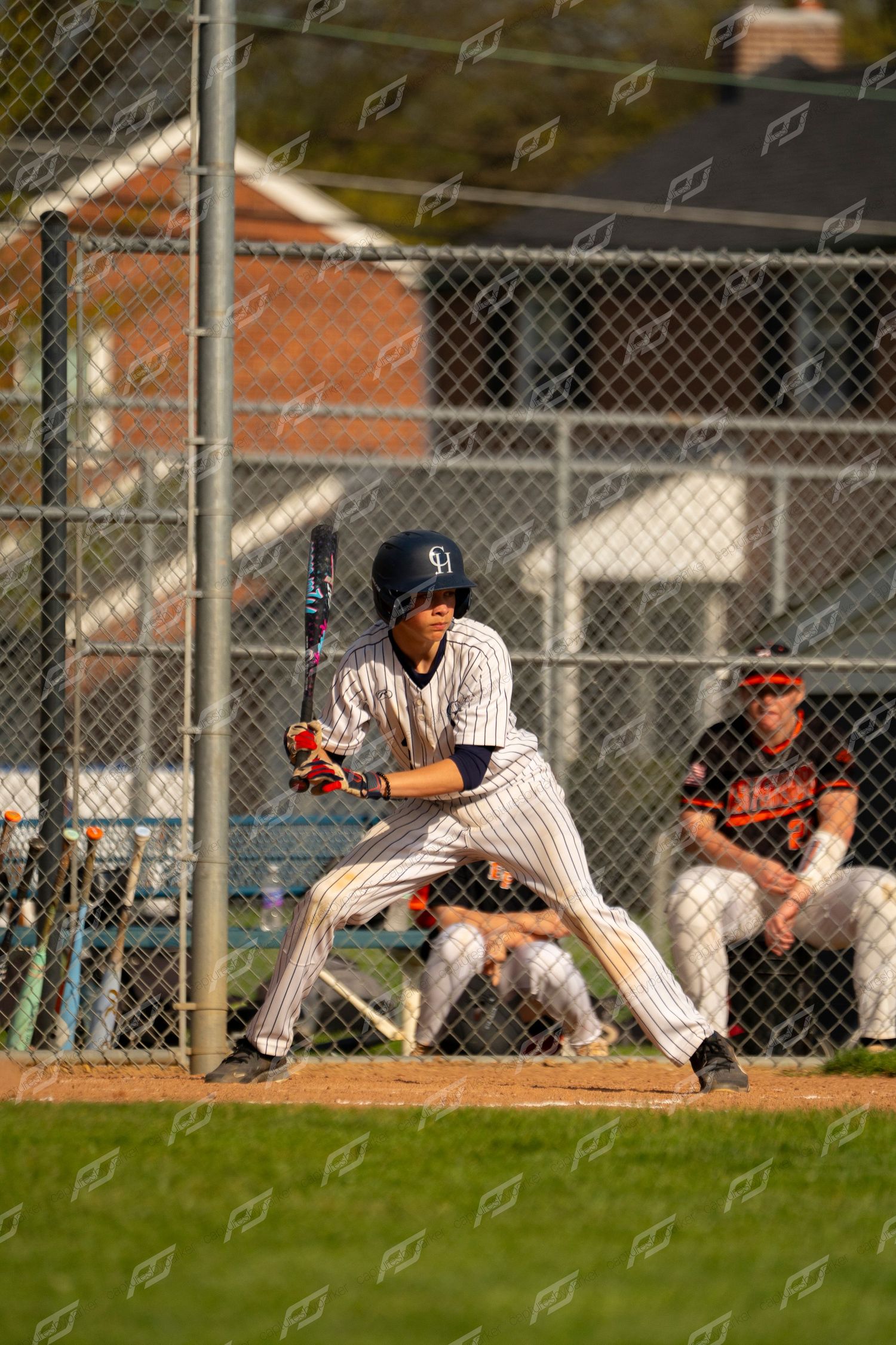 Baseball batter in pinstripe uniform standing ready in batting stance at home plate.
