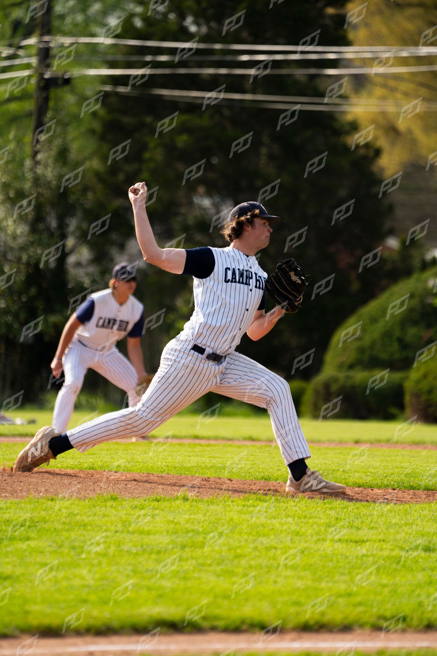 Camp Hill baseball pitcher follows through on a pitch delivery during an outdoor game.