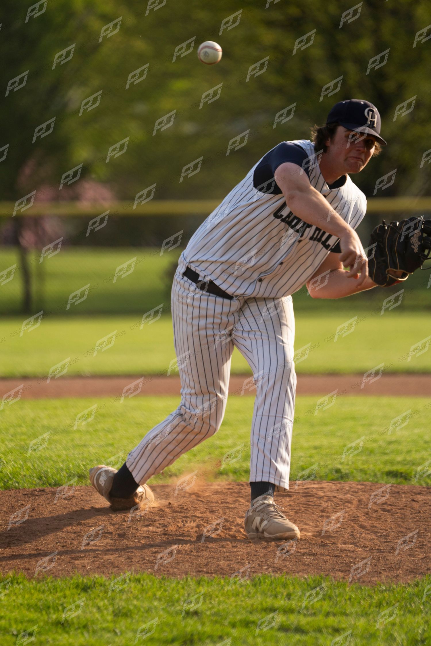 Camp Hill baseball pitcher releases a pitch from the mound during a golden-hour youth baseball game.
