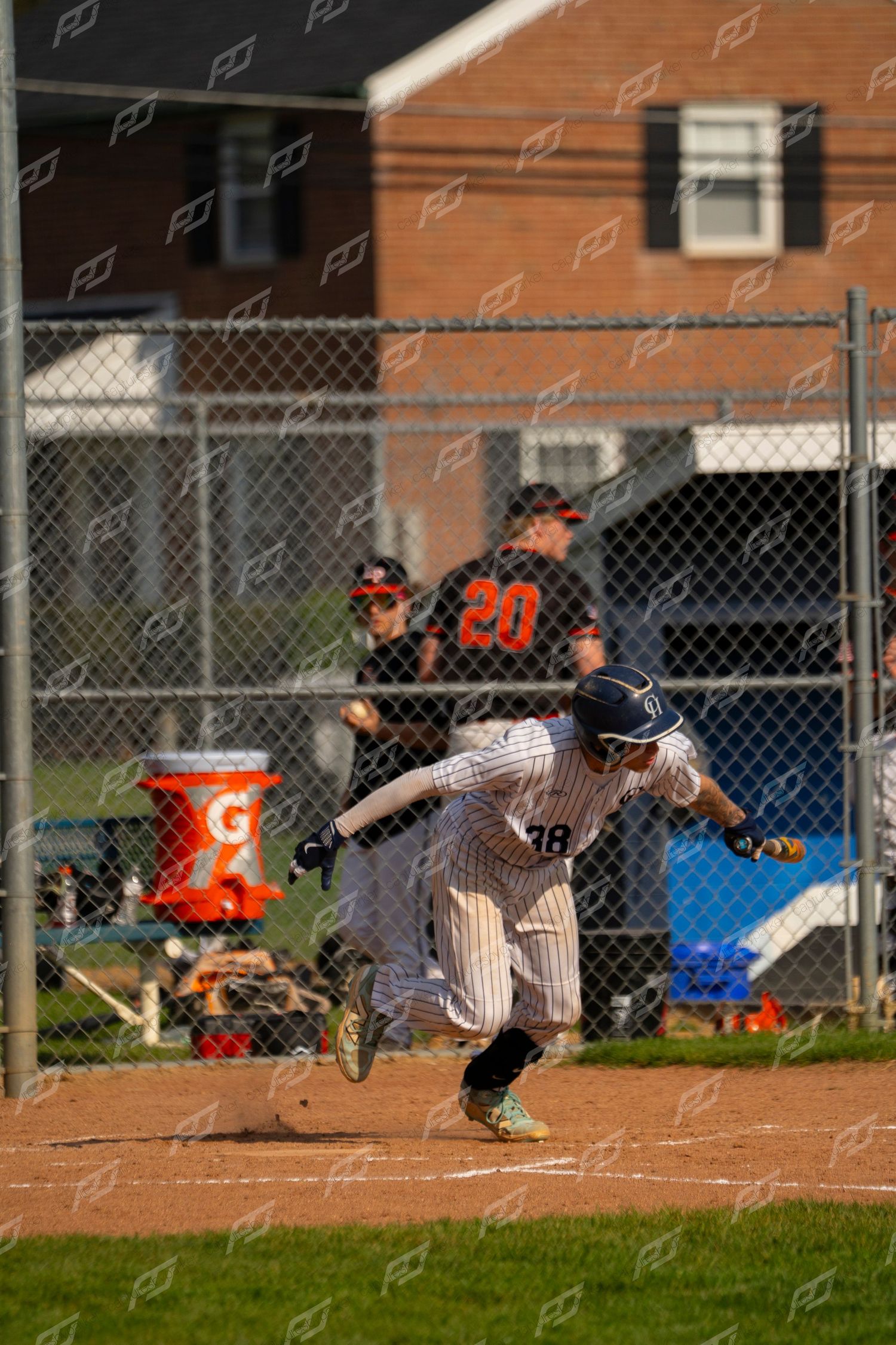 Baseball player #38 in pinstripe uniform sprints from home plate during an outdoor game.