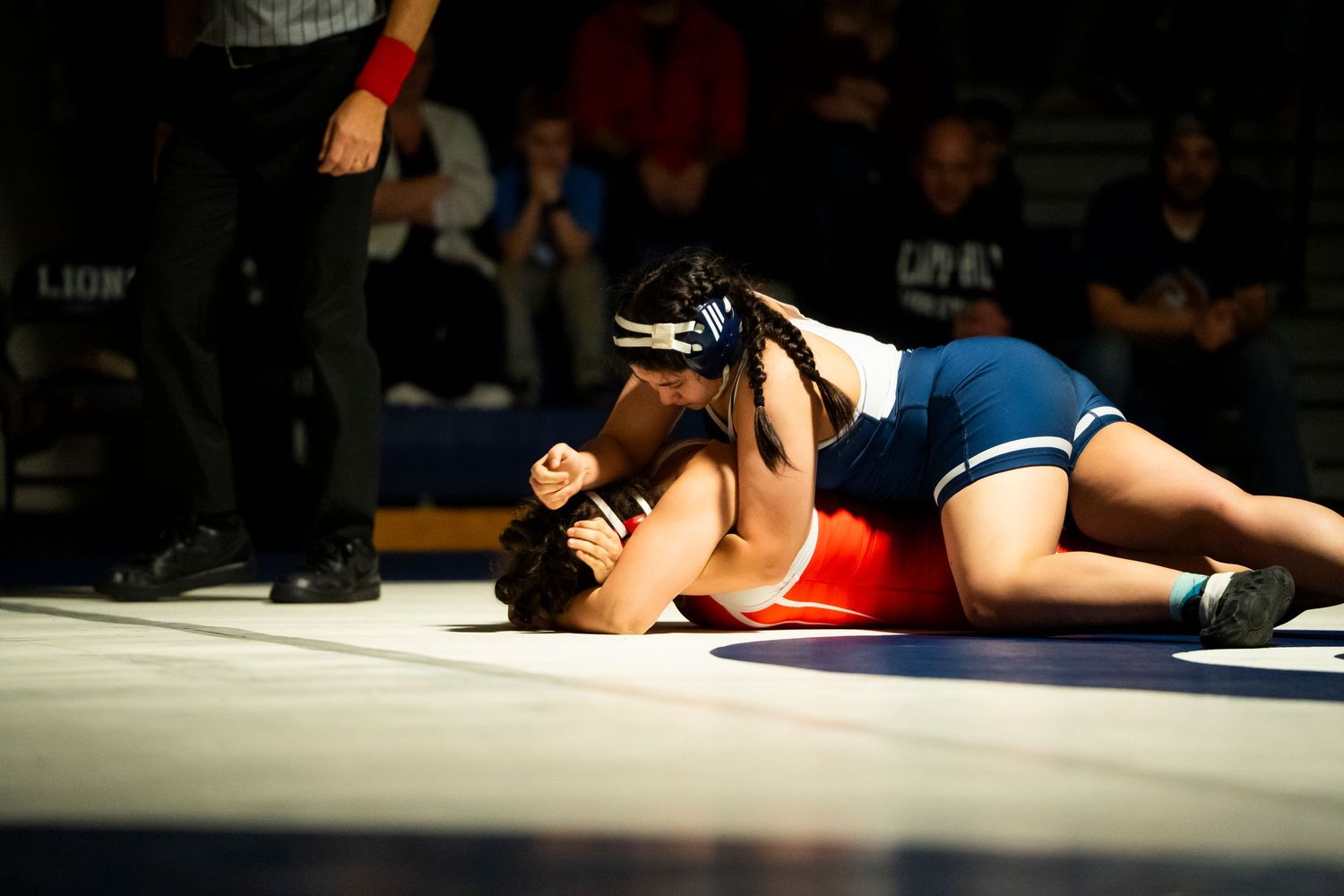 A wrestler pins his opponent to the mat during a competitive wrestling match.