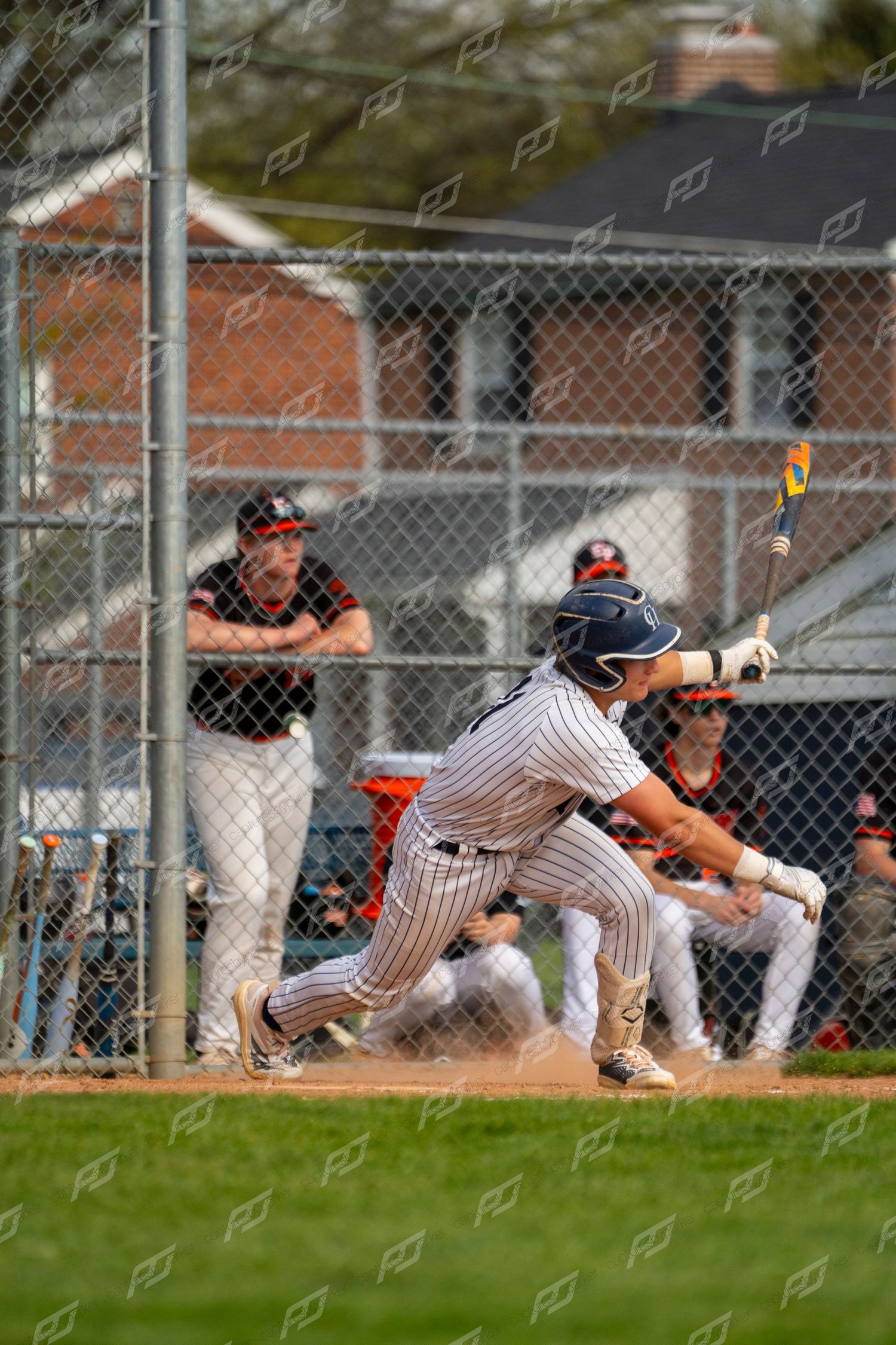 Baseball player in pinstripe uniform swings bat at home plate with dugout in background.
