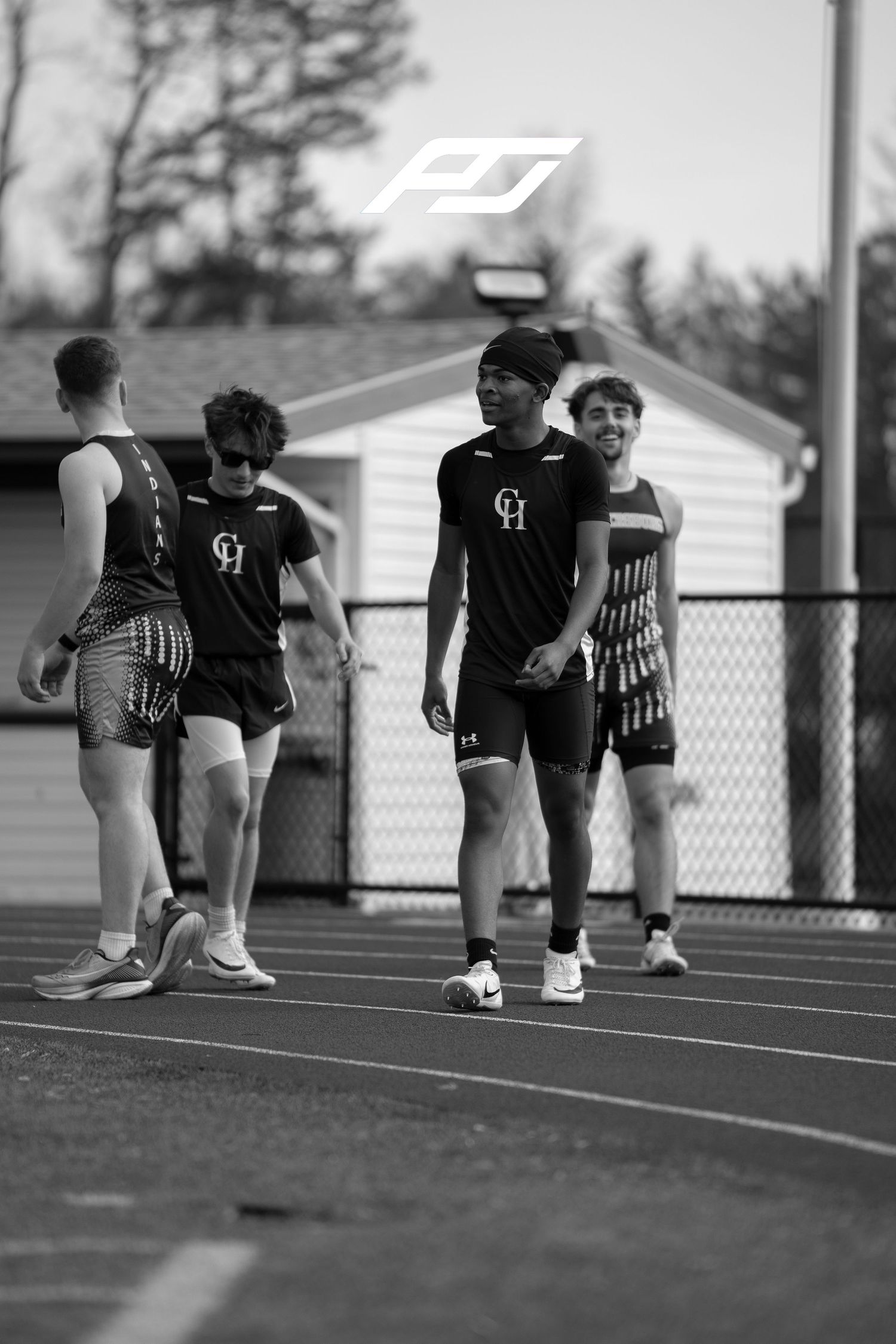 Four male CH track athletes walk together on track in black and white photo.