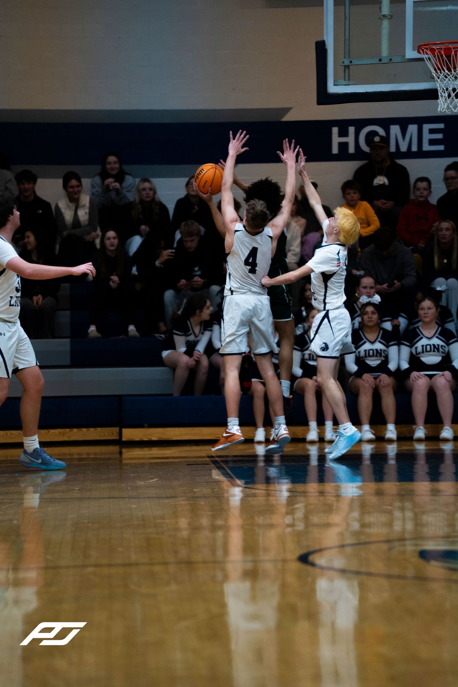 Camp Hill Lions player #4 attempts a jump shot while being defended during a home basketball game.