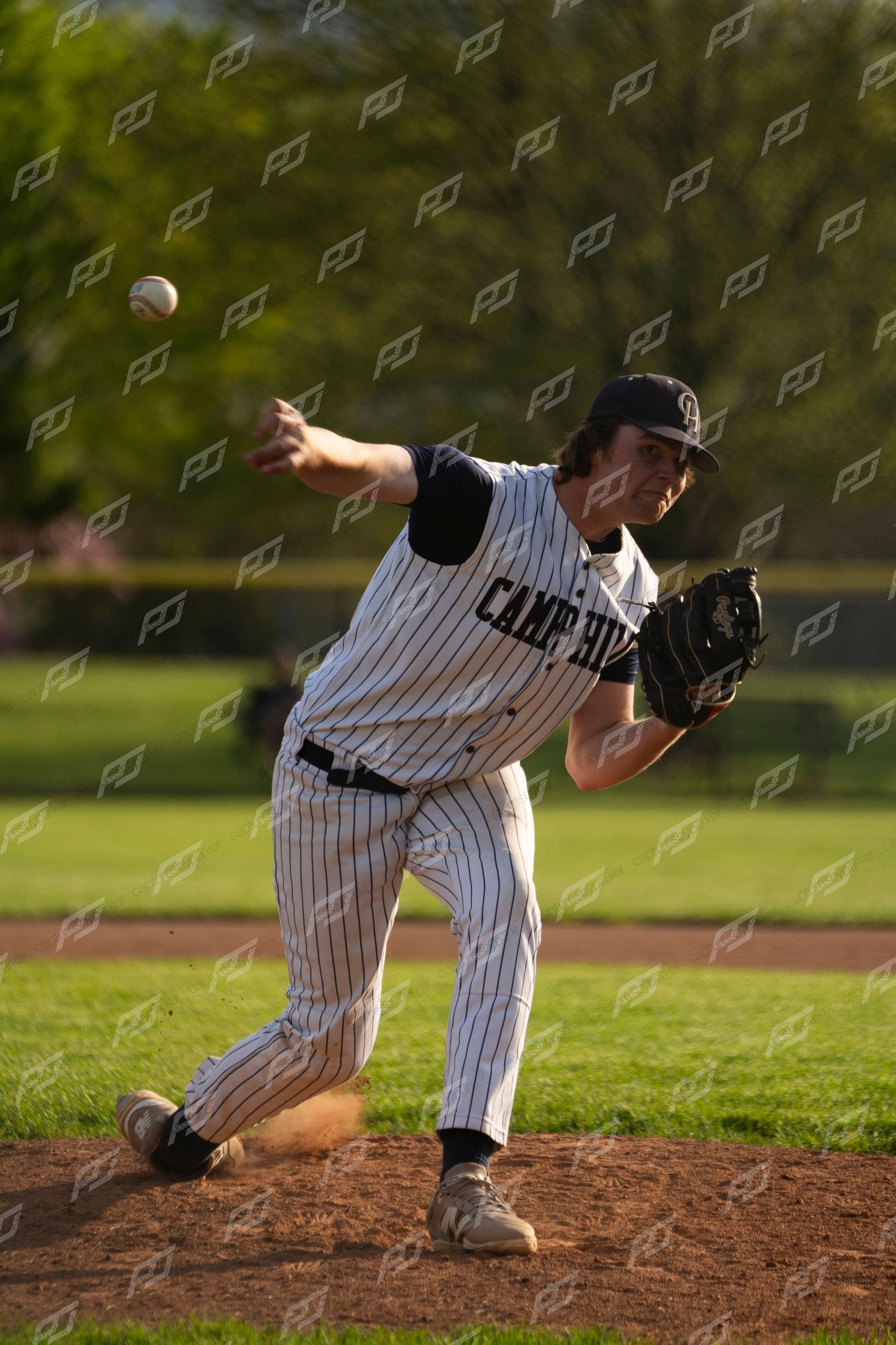 Camp Hill baseball pitcher winds up to throw a pitch during a well-lit outdoor youth baseball game.