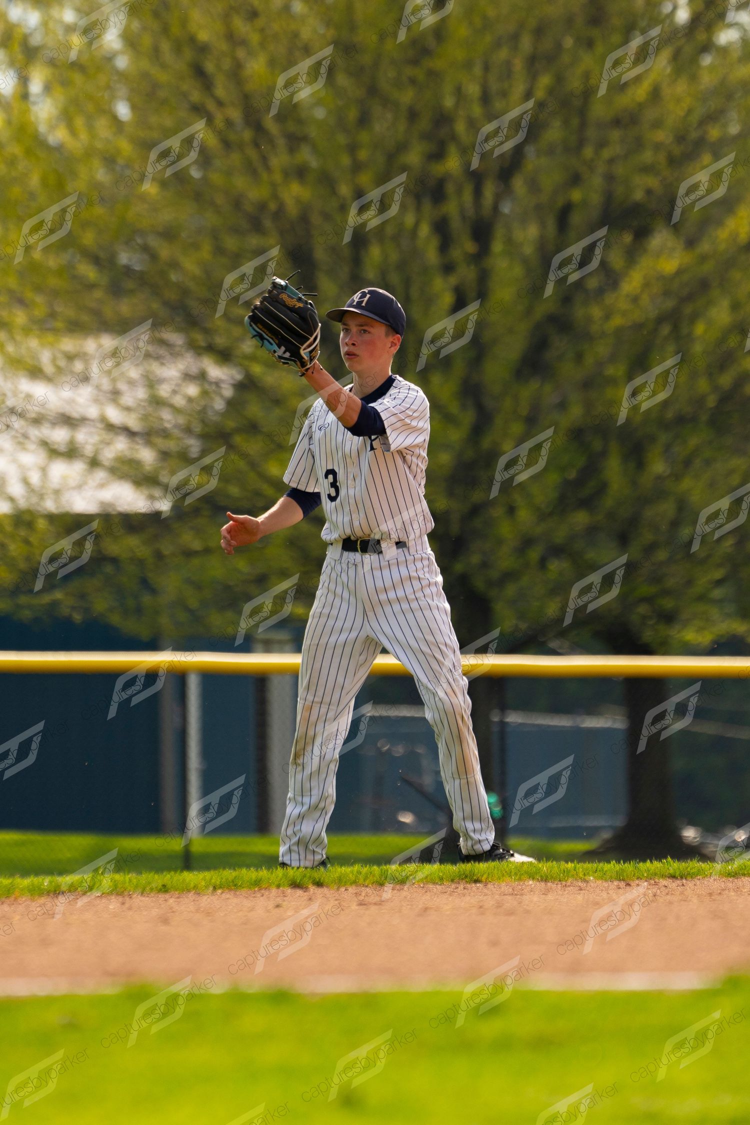 Youth baseball player #3 in white pinstripe uniform catching a fly ball in the outfield.