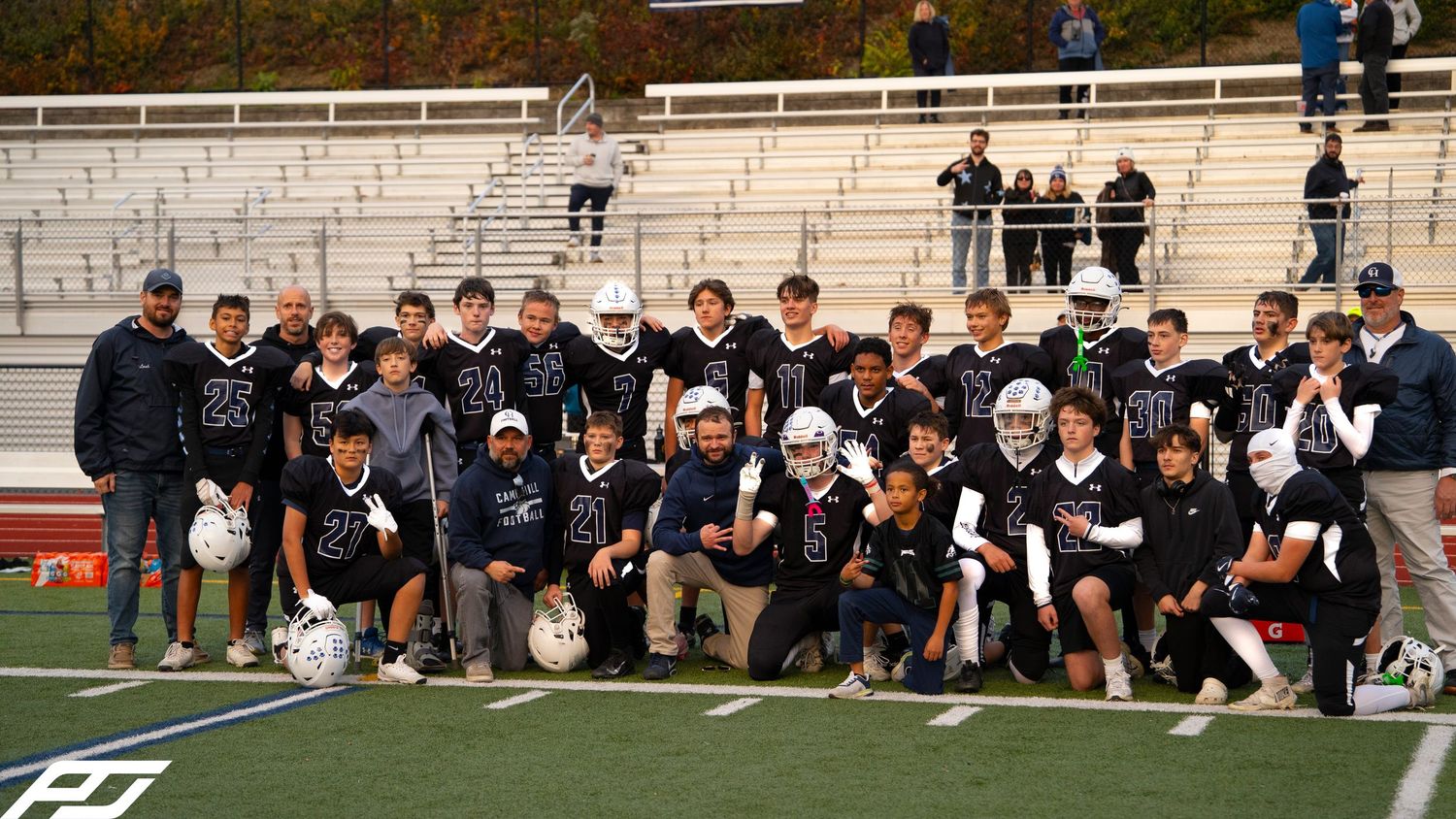 Youth football team poses together for a group photo on the field after a game.
