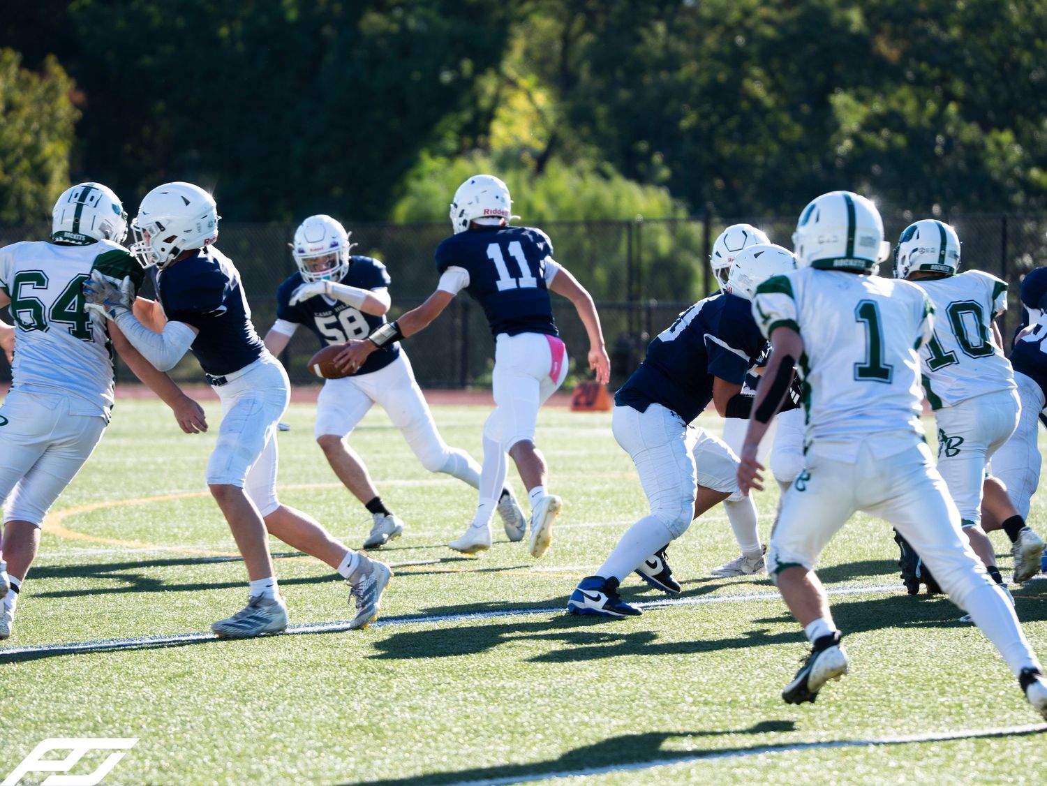 Youth football players in navy uniforms execute a play during a competitive game.