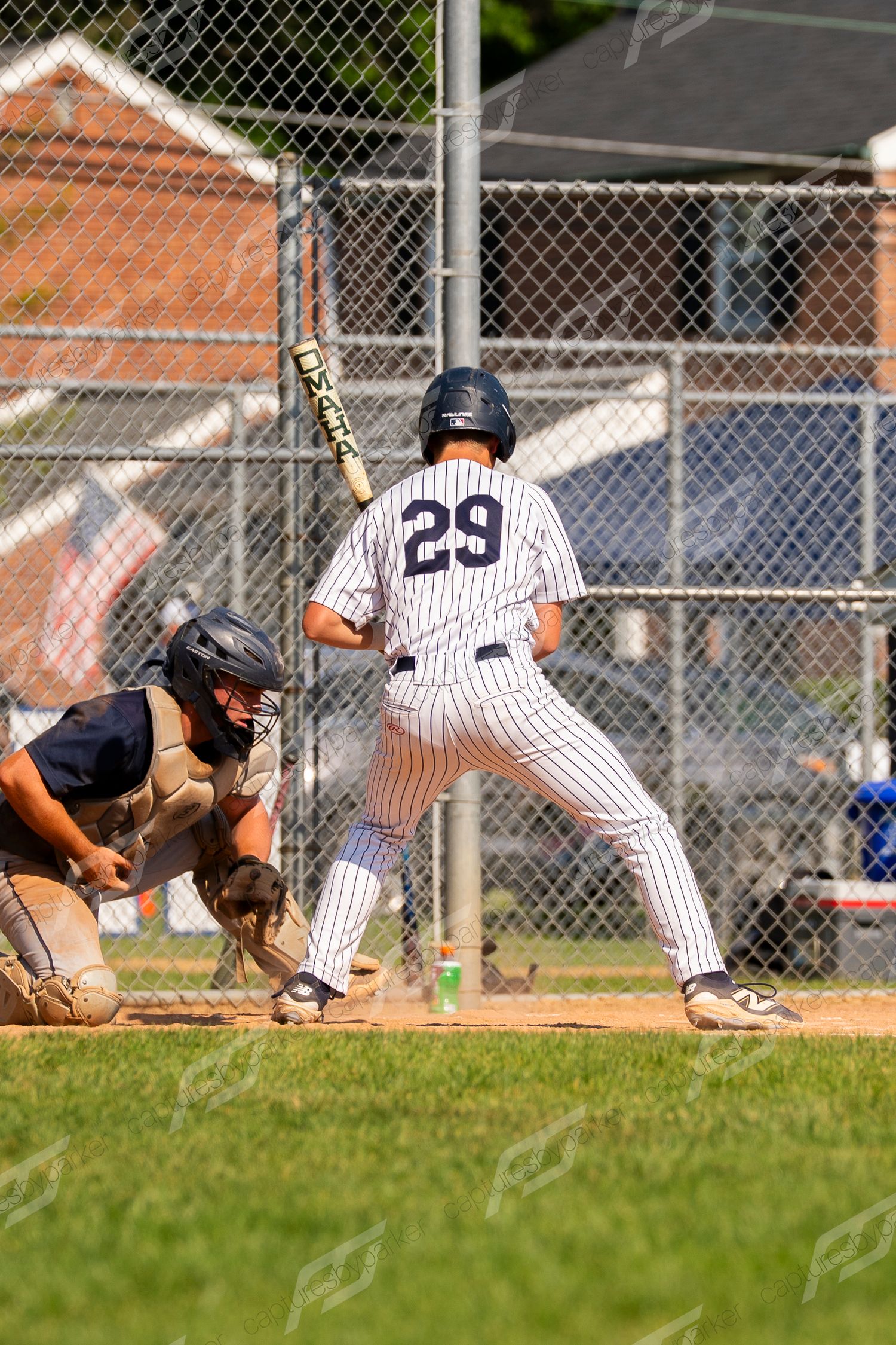 Baseball batter #29 in pinstripe uniform stands ready at the plate with catcher crouching behind.