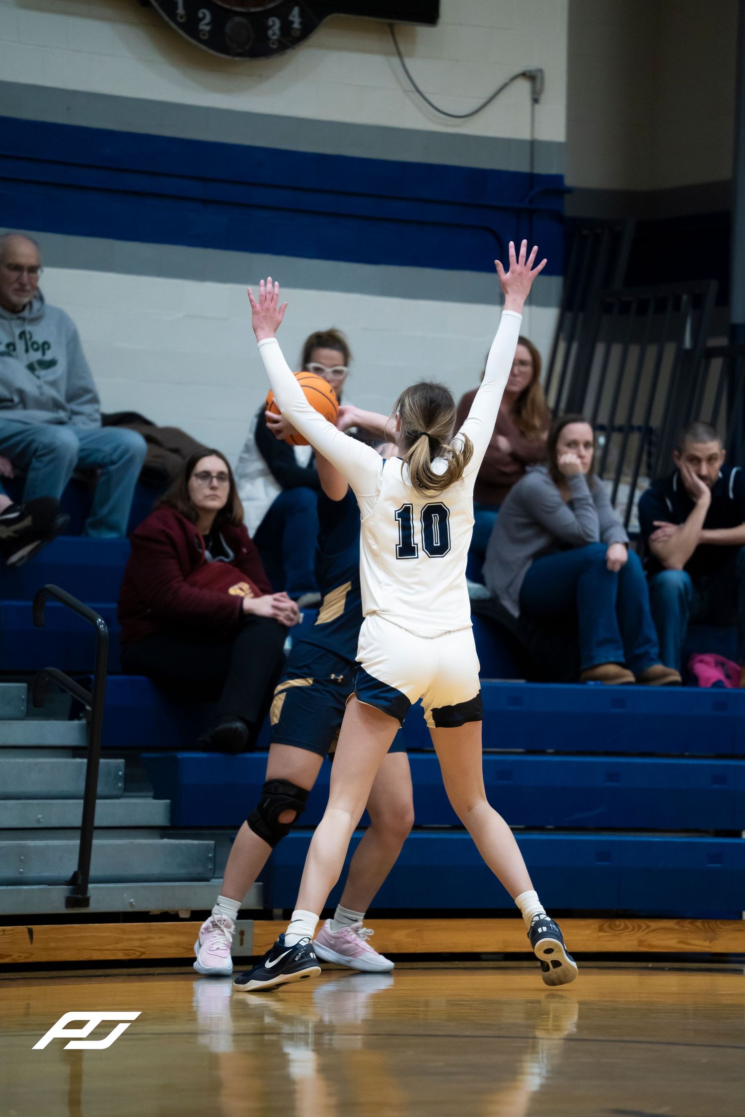 Lions number 10 raises both hands to defend a pass during a girls high school basketball game.