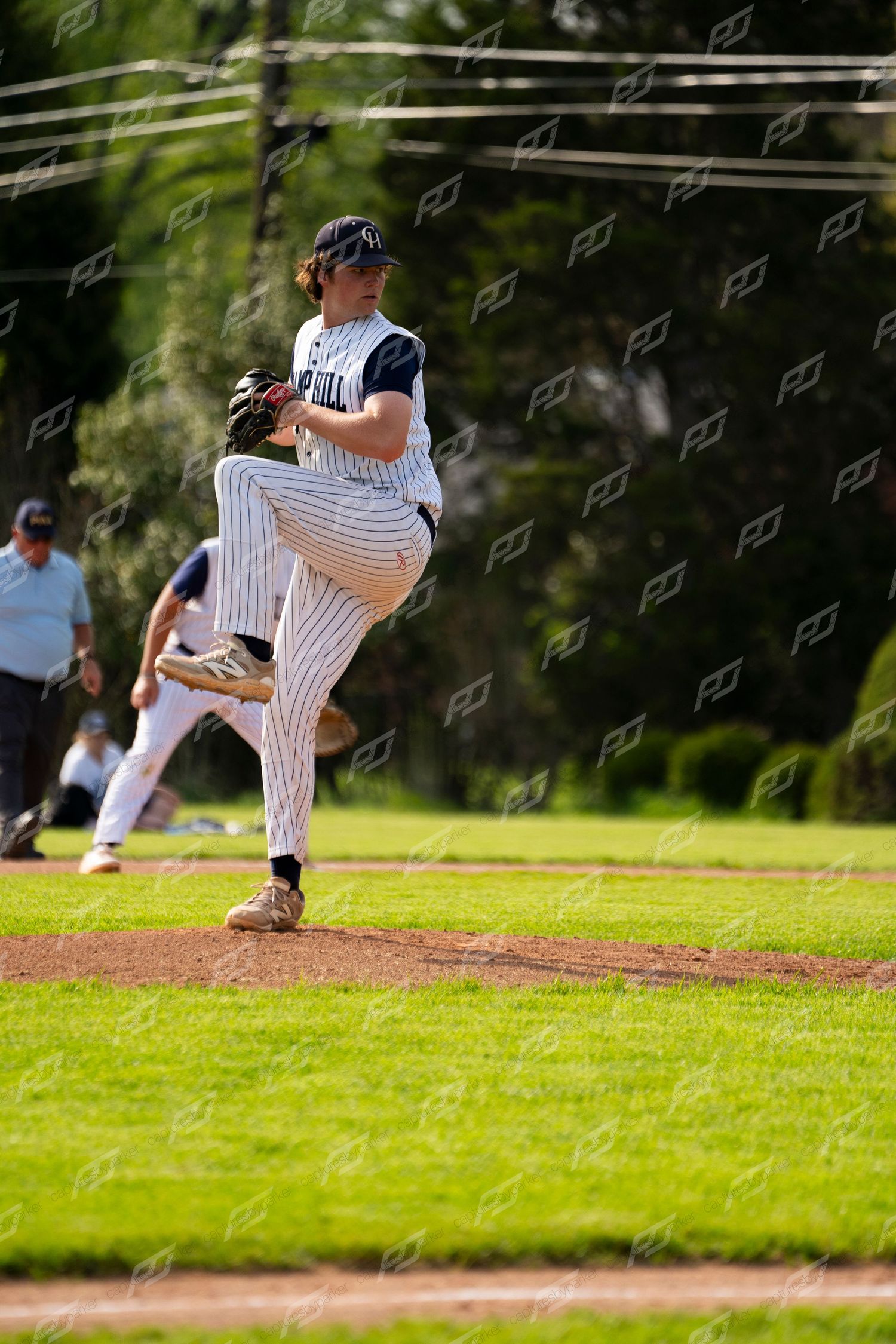 Camp Hill pitcher winds up on the mound in a high-leg kick during a baseball game.