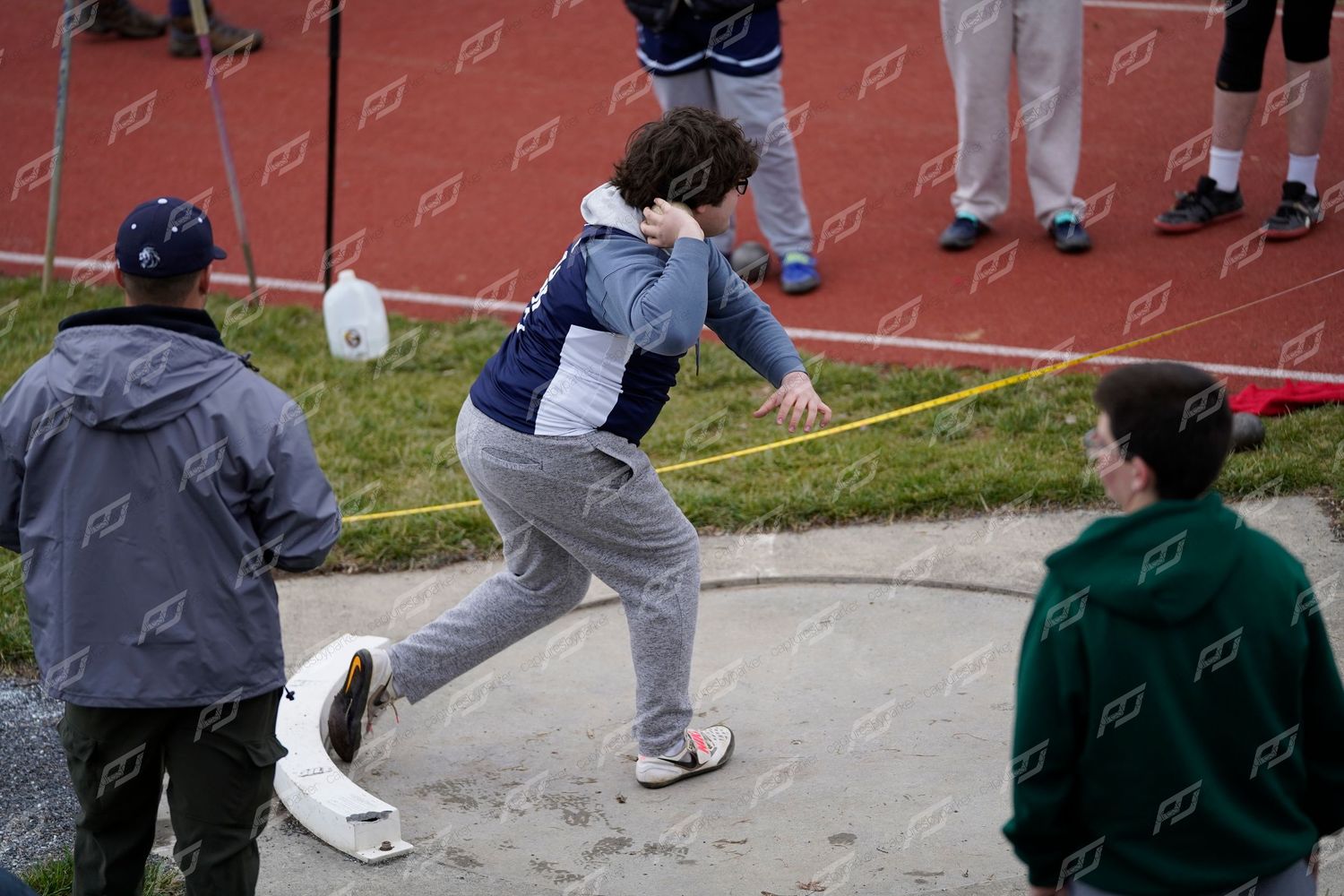High school athlete follows through on a shot put throw during an outdoor track and field competition.