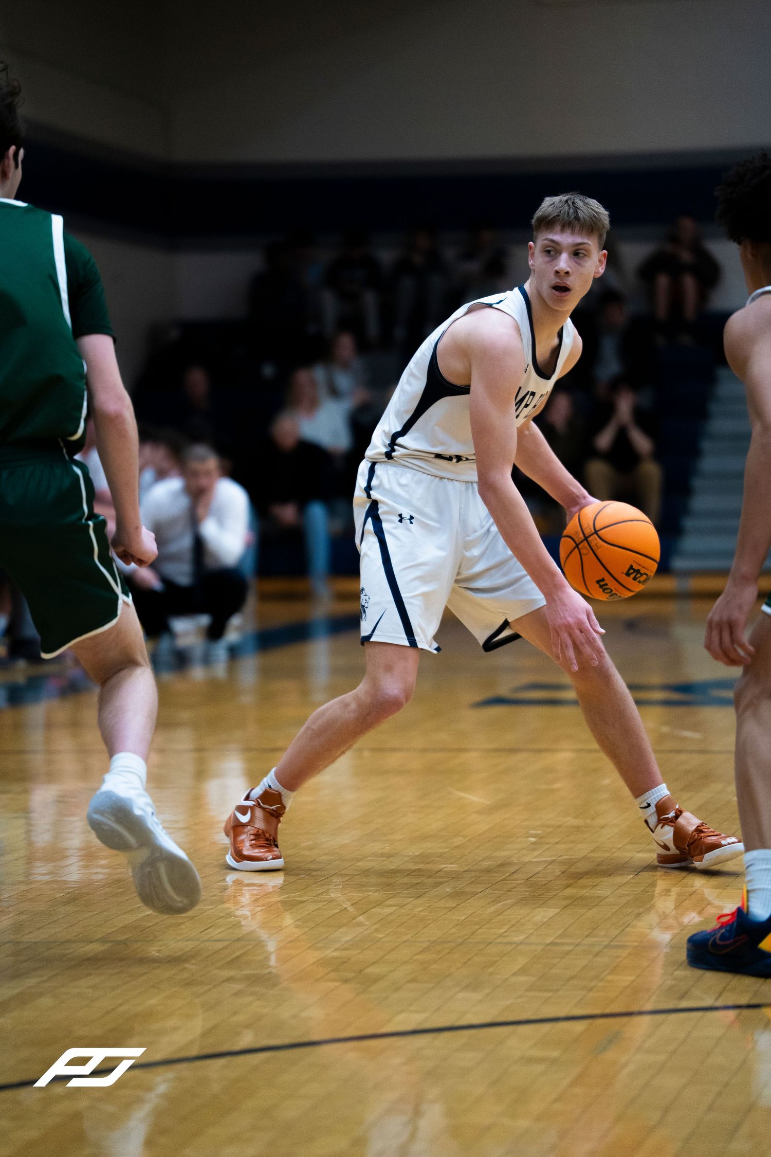 Camp Hill Lions basketball player dribbles ball in white uniform during home game against Trinity.