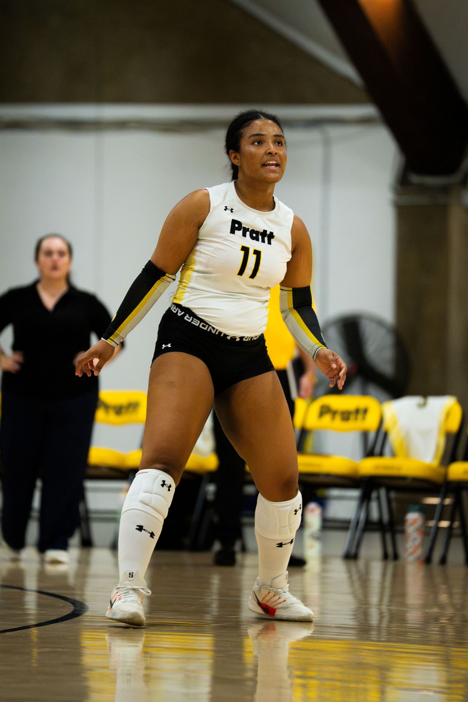 Pratt volleyball player #11 in white and black uniform ready for play on indoor court.