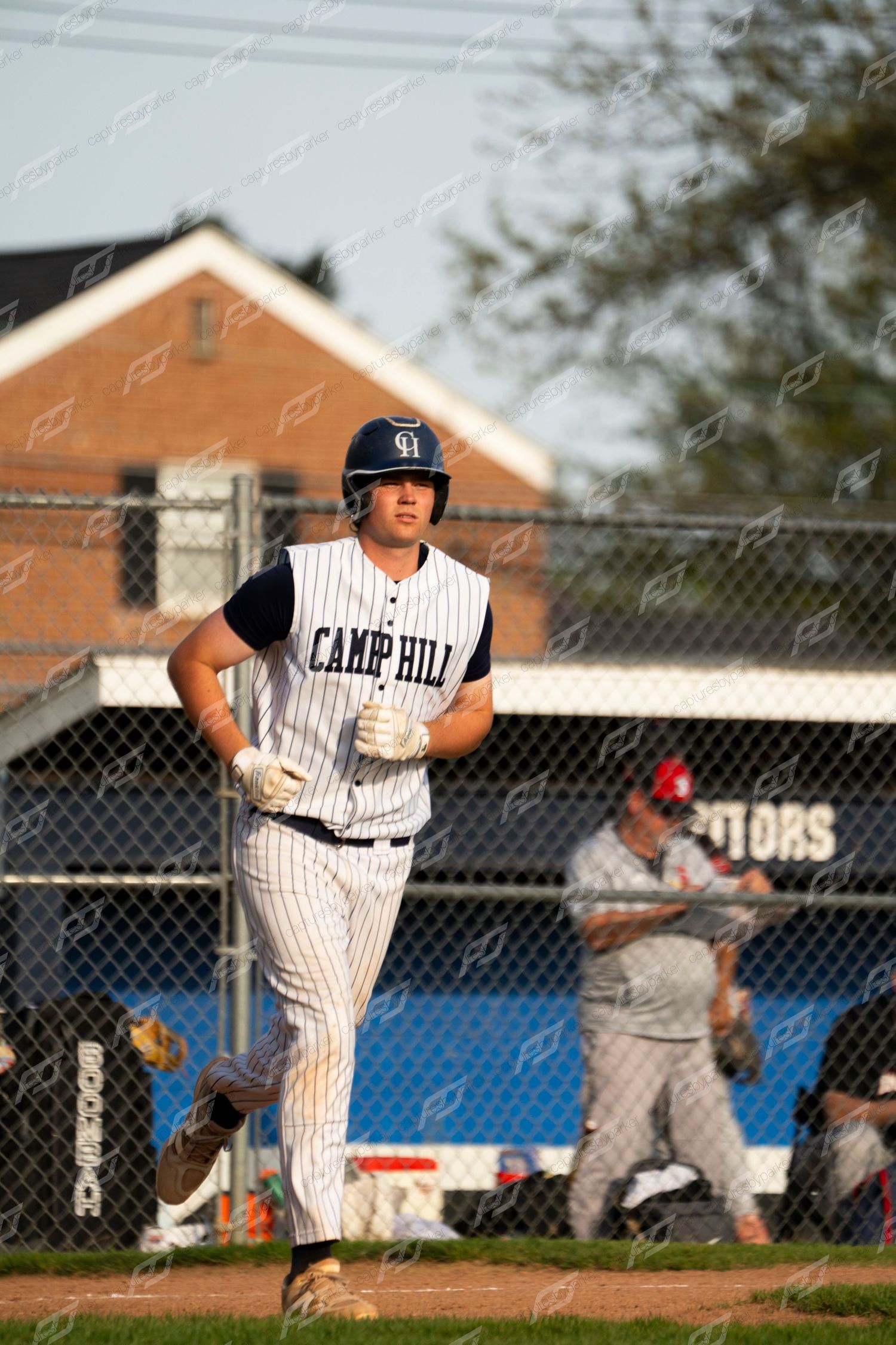 Camp Hill baseball player jogs toward home plate during a game on a sunny day.