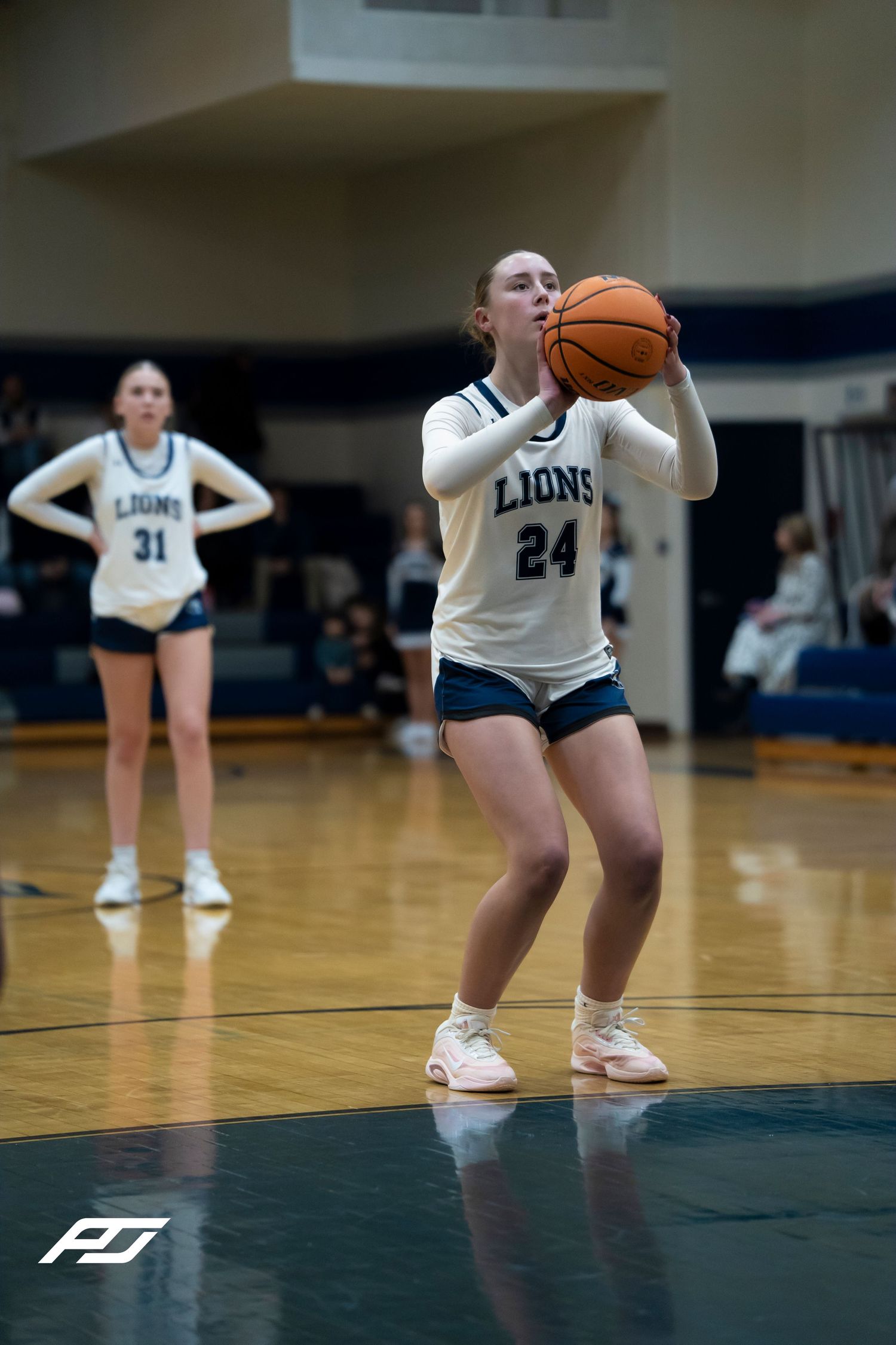 Lions #24 female player prepares to shoot free throw during high school basketball game.