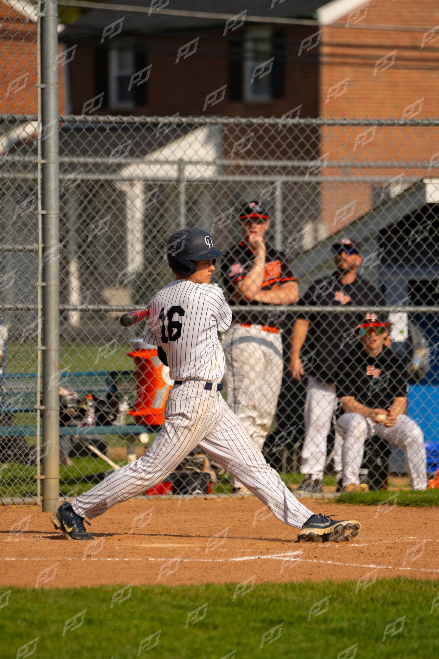 Youth baseball player #16 in pinstripe uniform completing a swing at home plate during a game.