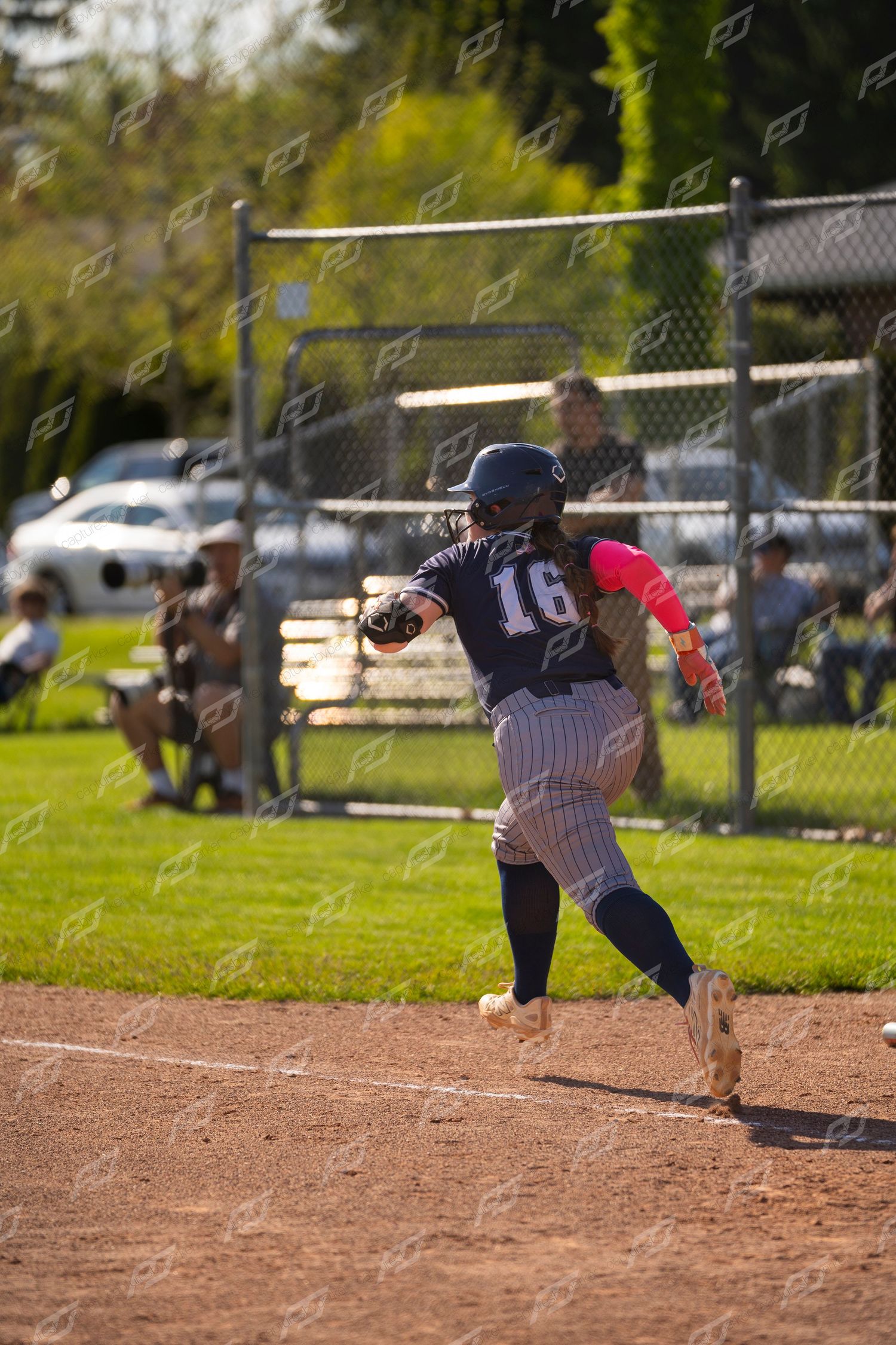 Female softball player number 16 running the bases during a sunny outdoor softball game.