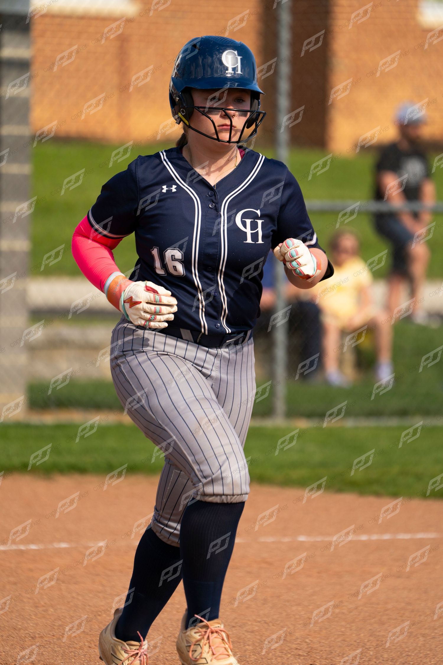 Female softball player number 16 in CH navy uniform runs the bases during a game.