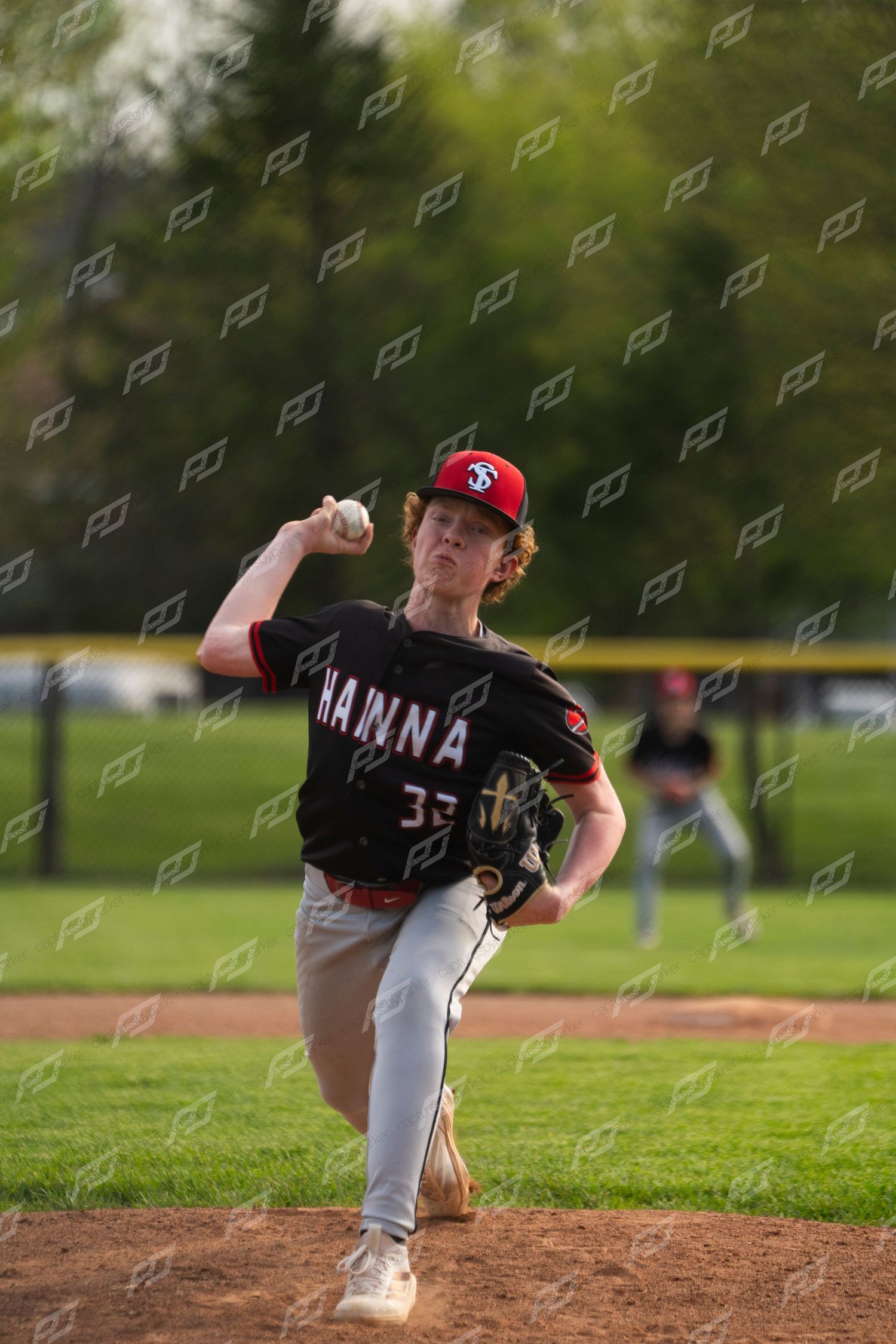 Hanna baseball pitcher number 35 in black uniform winding up to throw a pitch from the mound.