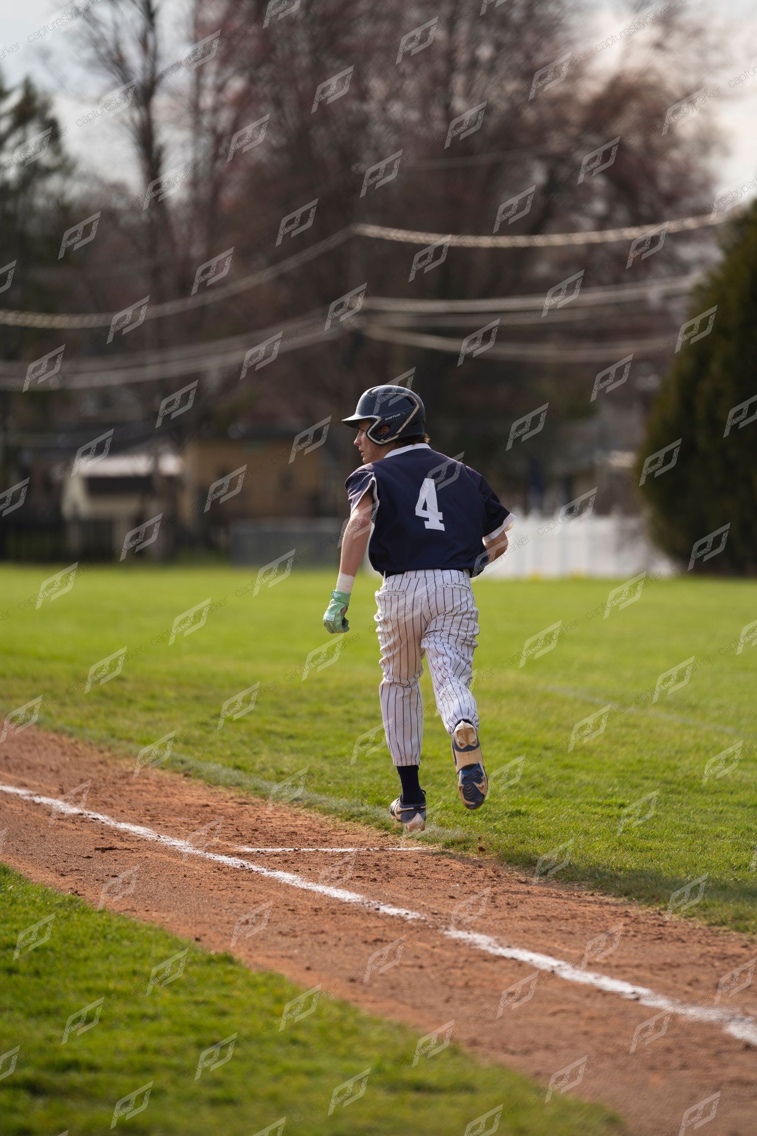 Youth baseball player #4 in navy pinstripe uniform sprinting along the baseline.