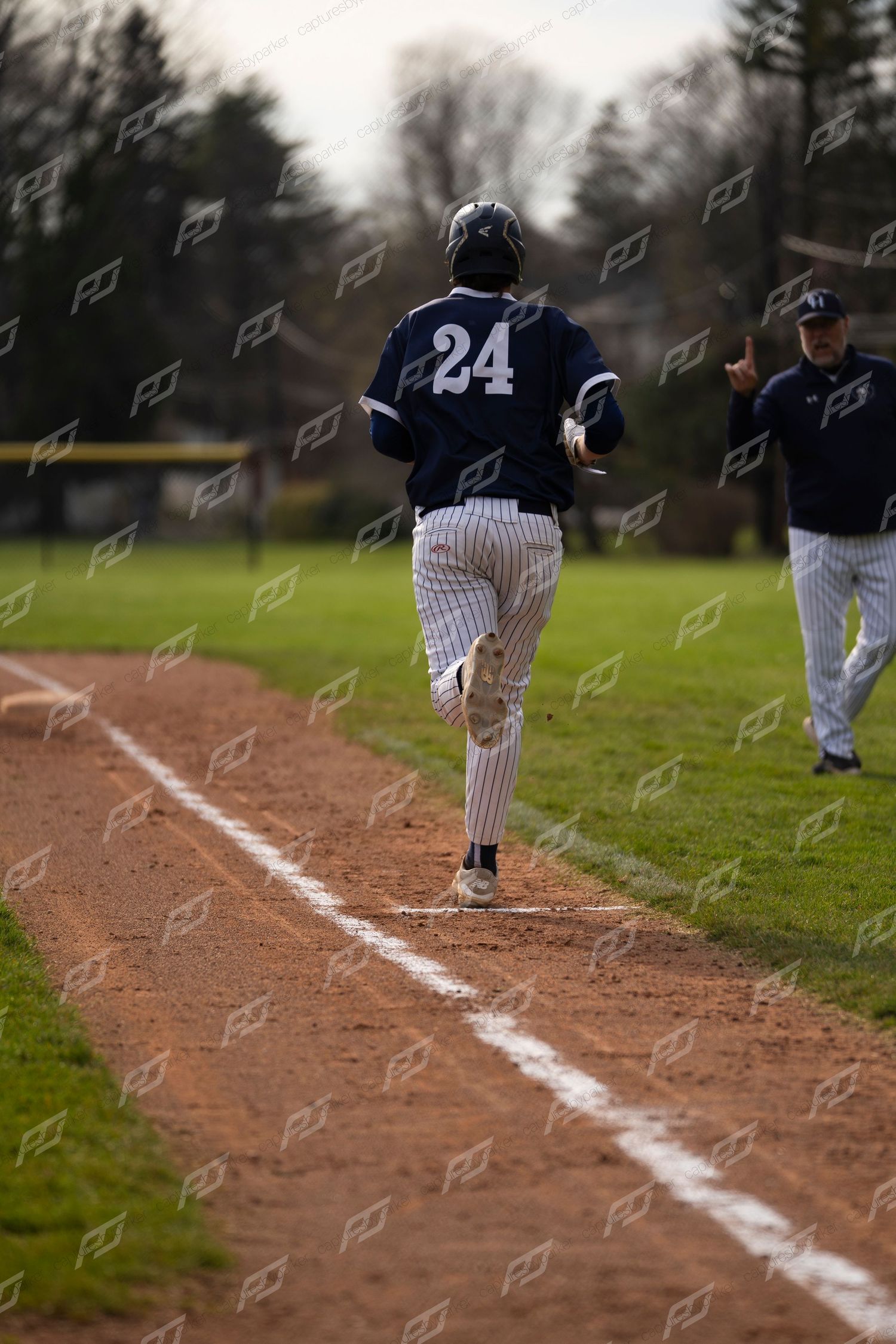 Baseball player #24 in navy pinstripe uniform runs the baseline during a game.