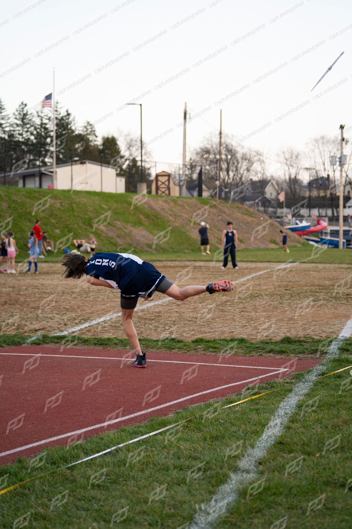 Young male athlete completing javelin throw at outdoor track competition.