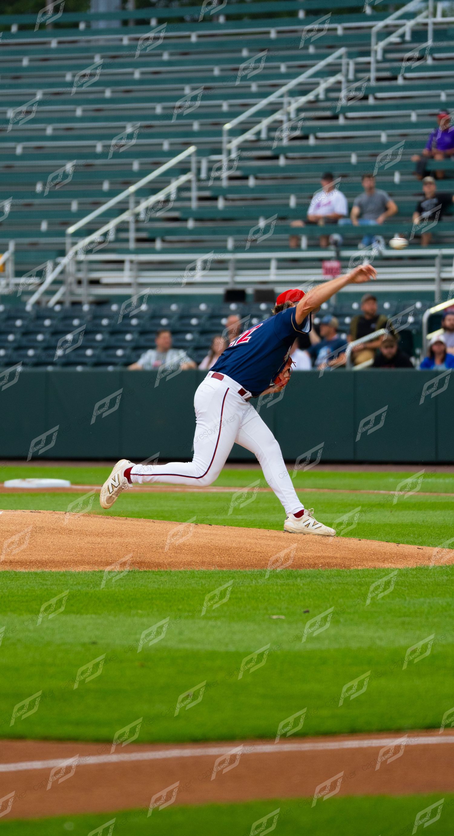 Minor league baseball pitcher in white uniform delivering a pitch from the mound during a game.