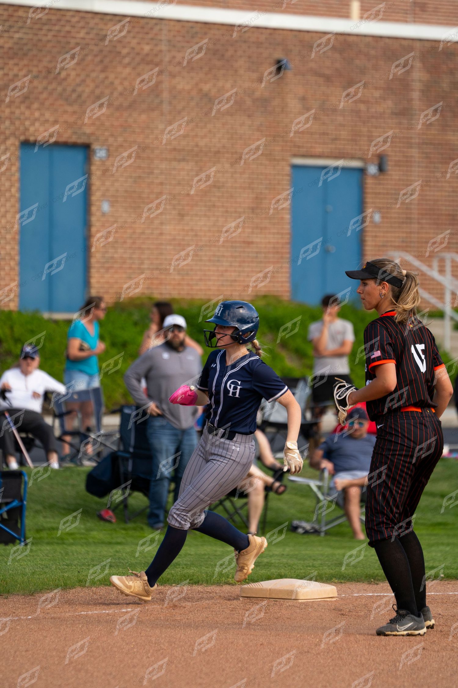 CH softball player rounds first base past the opposing team's first baseman during a game.