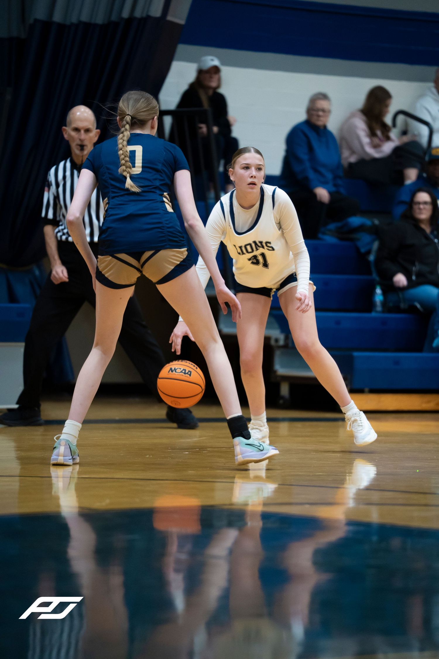 Lions #41 female basketball player plays defense against an opponent dribbling during a high school girls game.