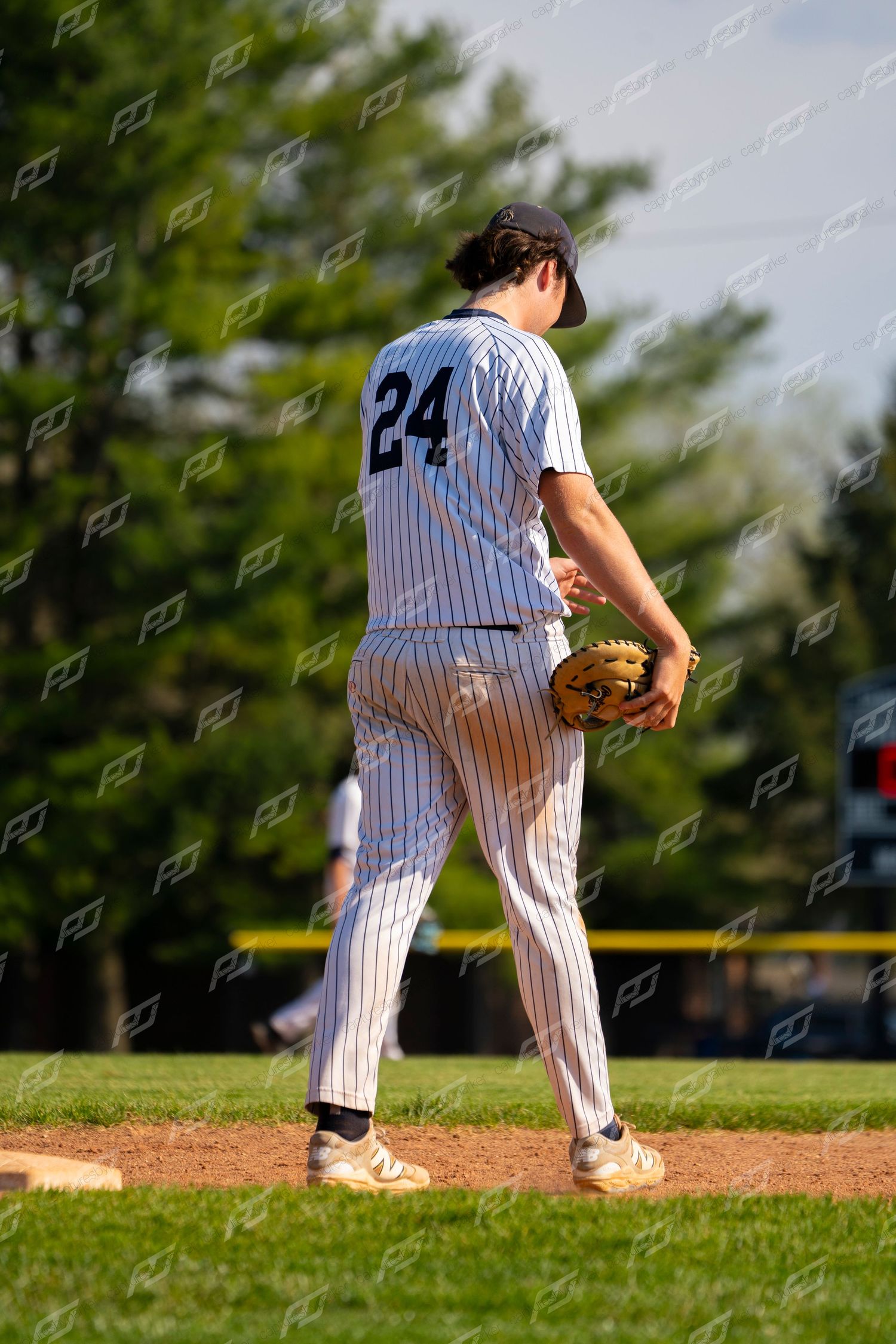 Baseball pitcher #24 in pinstripe uniform prepares to pitch on mound viewed from behind.