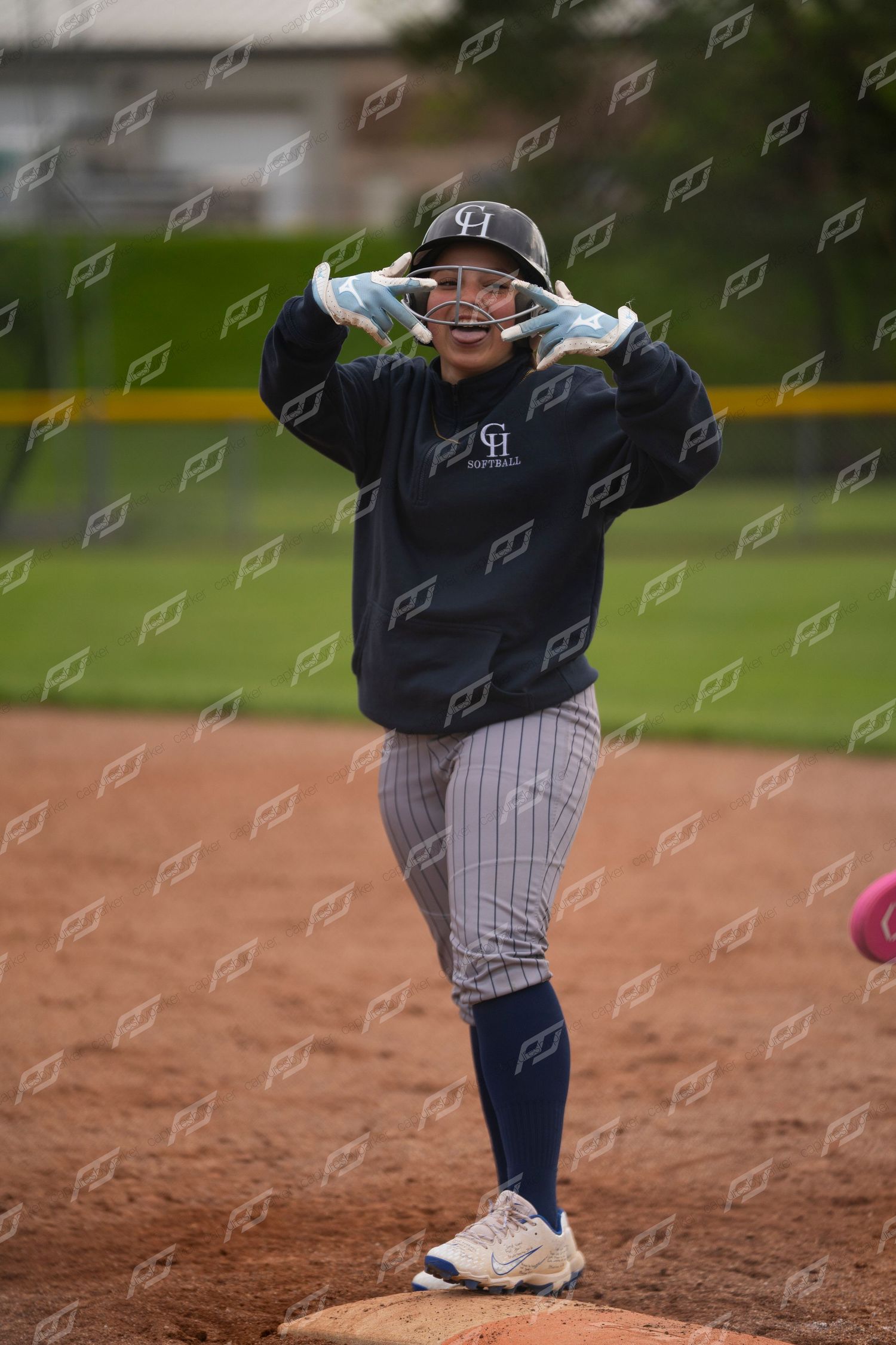 Smiling softball player adjusts helmet on base wearing navy GI softball sweatshirt.