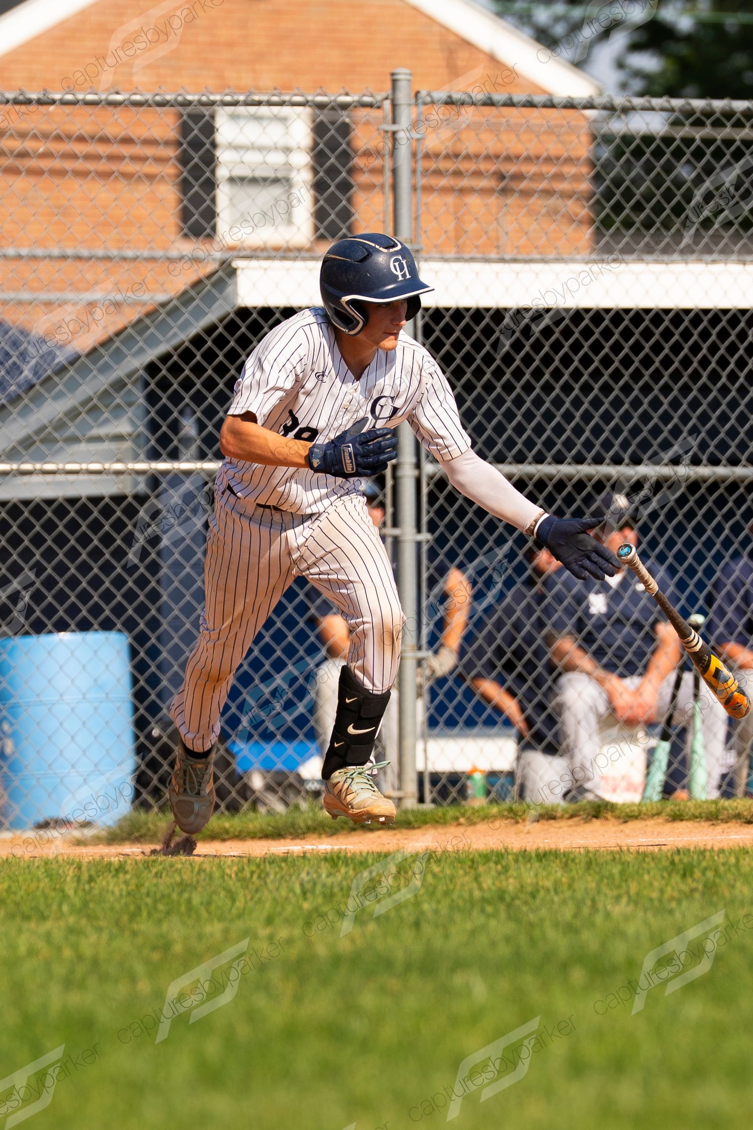 Youth baseball player in pinstripe uniform running from home plate after making contact with the ball.