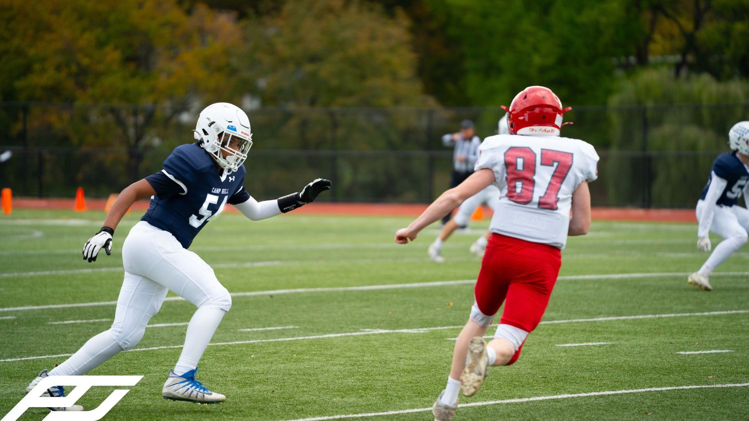 Football player in navy uniform defends against red-jersied number 87 receiver.