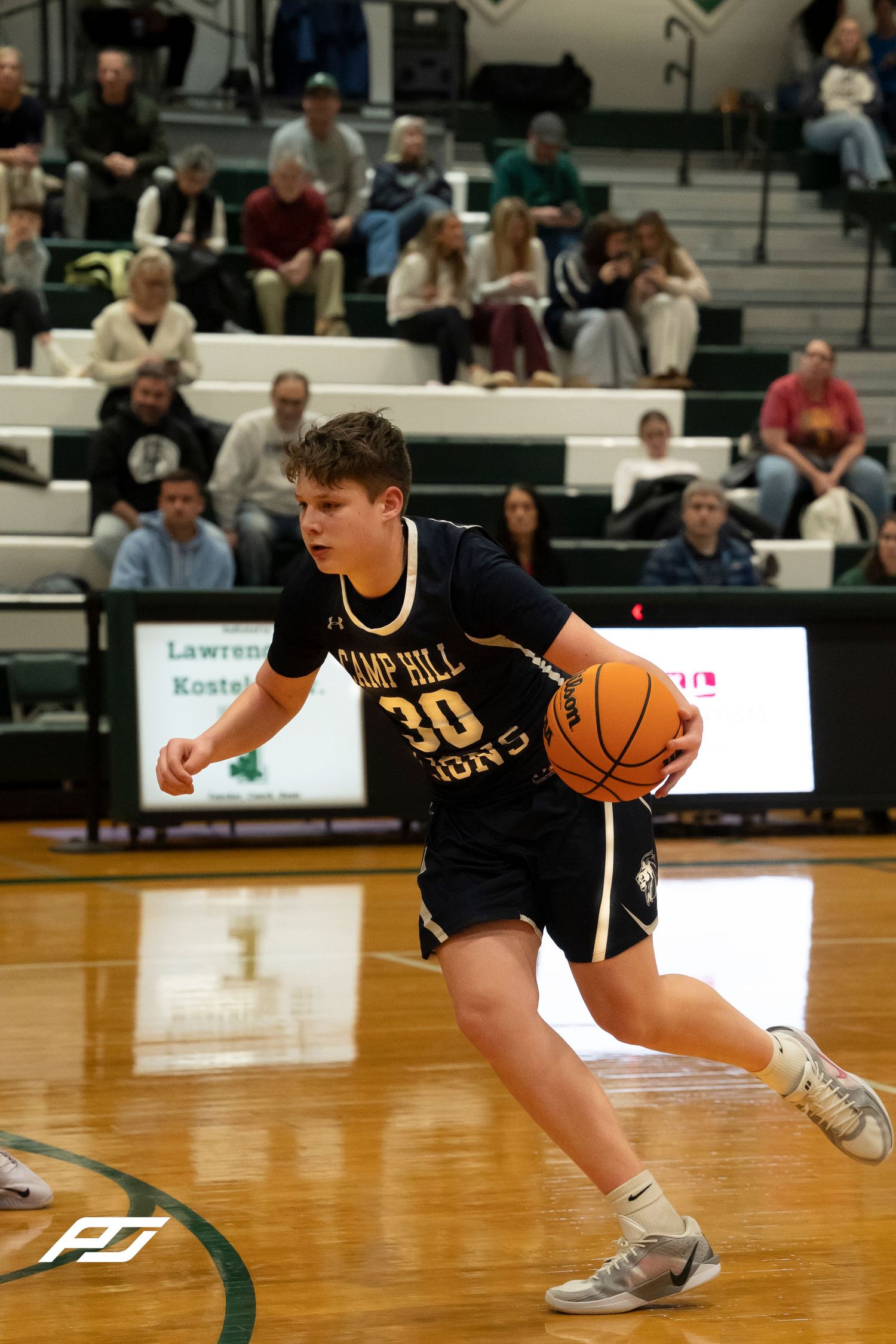 Camp Hill Lions number 30 dribbles the ball during a high school basketball game against Trinity.