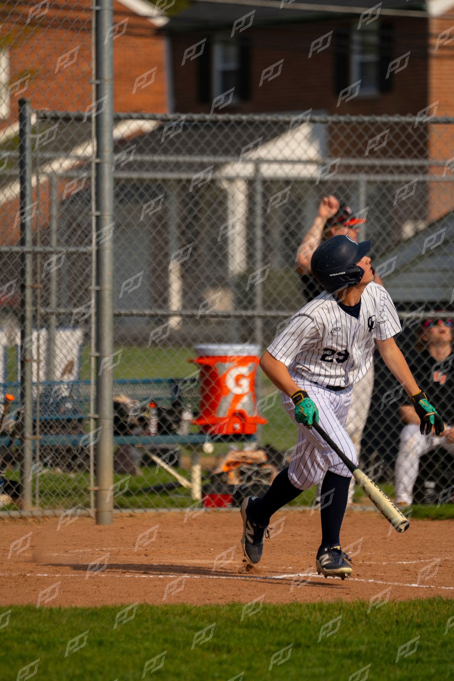 Young baseball player #29 in pinstripe uniform running after hitting the ball during a game.